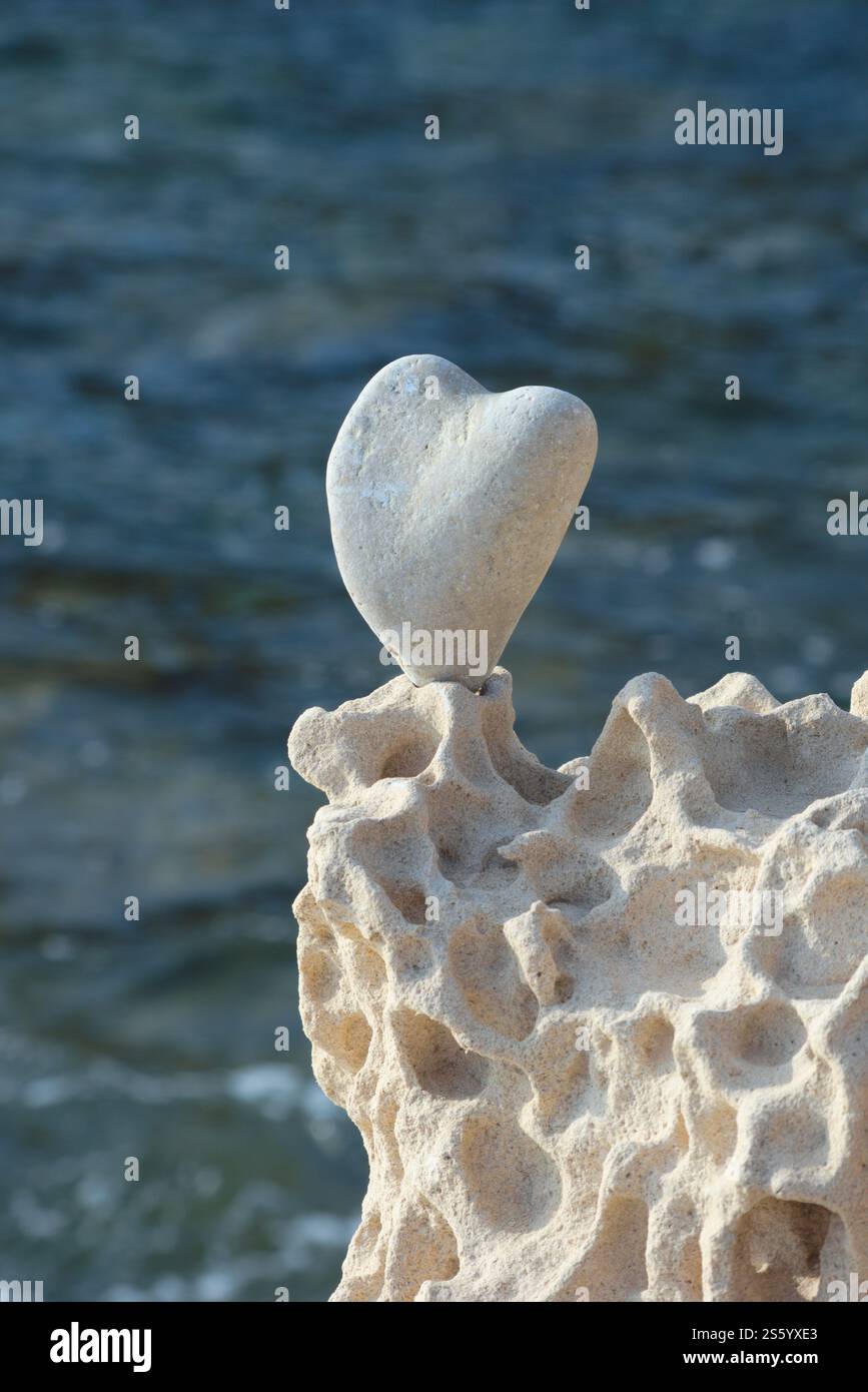 Herzförmiger Kieselstein, auf der Klippe. Sardinien, Italien. Abstraktes Konzept: Liebe, Emotionen, Verlieben, Zuneigung, Liebe zur Natur-Meer Stockfoto