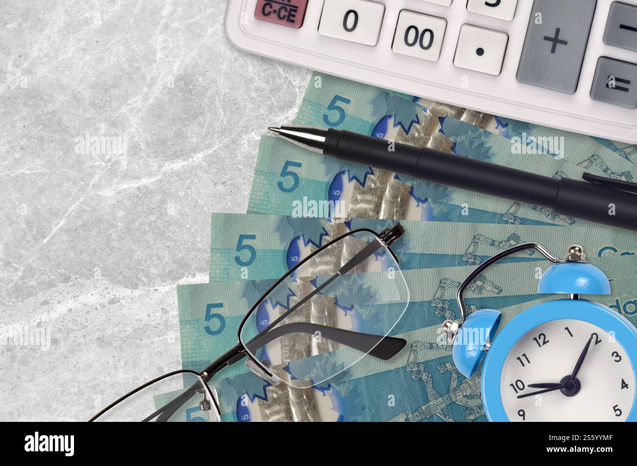 5 kanadische Dollarscheine und Taschenrechner mit Brille und Stift. Geschäftsdarlehen oder Steuerzahlung Saisonkonzept. Finanzplanung und Zeit für die Zahlung von Steuern. Stockfoto