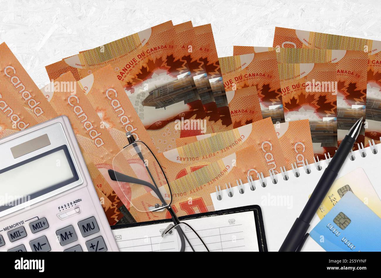 50 kanadische Dollarscheine und Taschenrechner mit Brille und Stift. Steuerzahlungssaisonkonzept oder Investitionslösungen. Finanzplanung oder Buchhalter Stockfoto