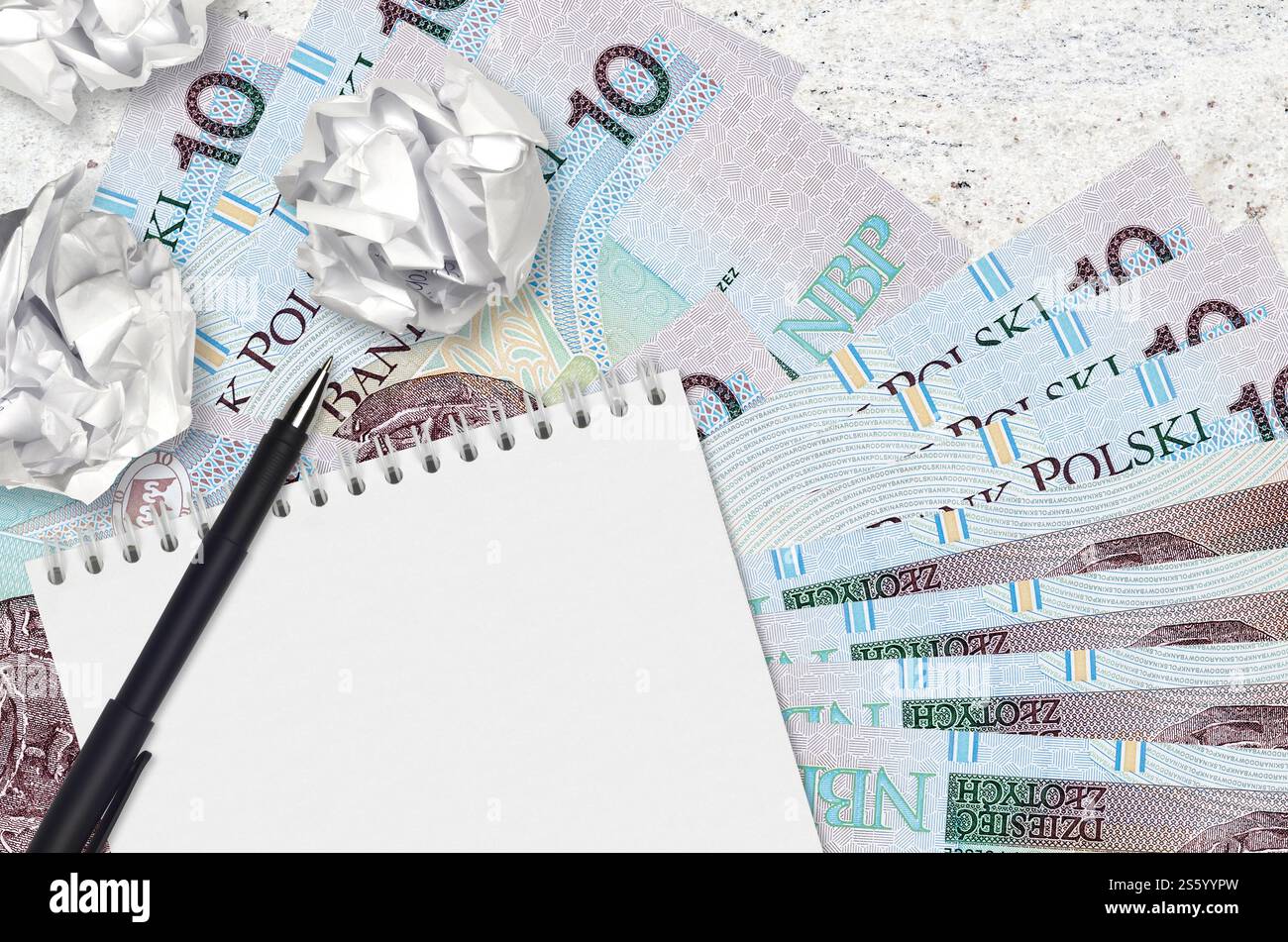 10 polnische Zloty-Scheine und Kugeln aus zerknittertem Papier mit Notizblock. Schlechte Ideen oder weniger Inspirationskonzept. Suche nach Ideen für Investitionen. 10 Polnisch Stockfoto