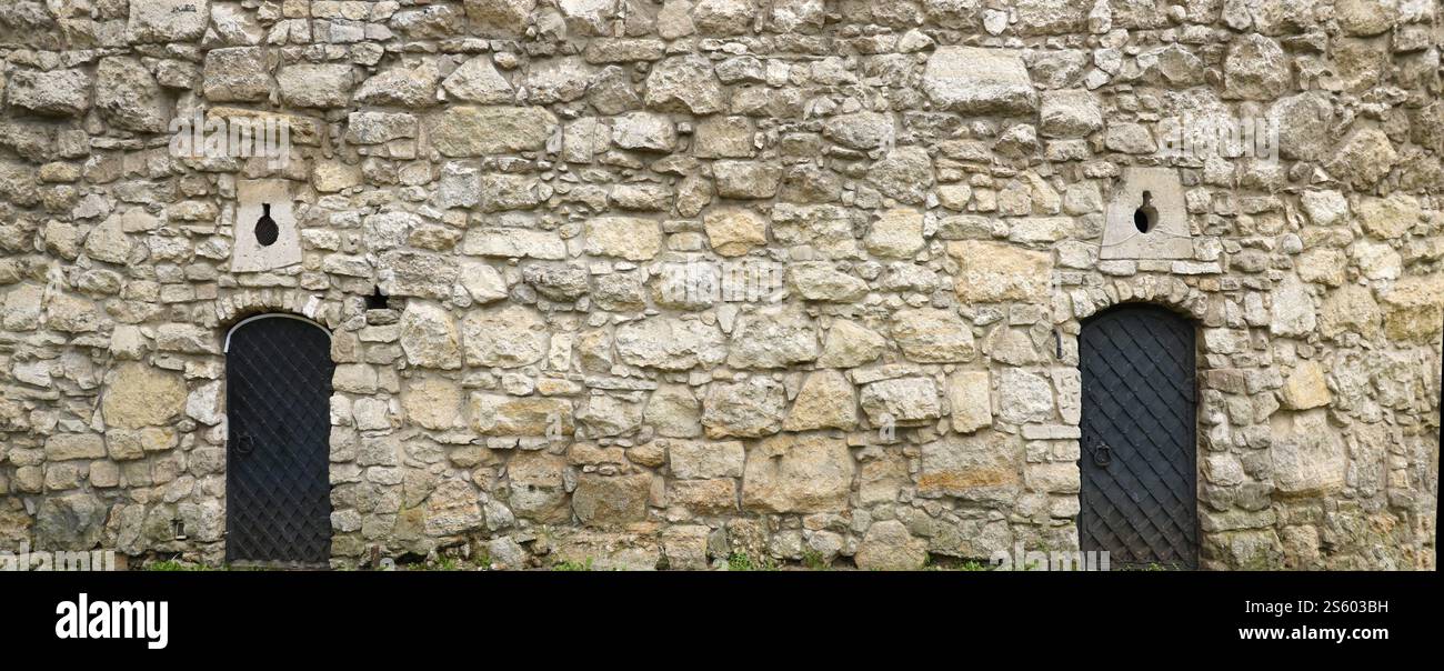 Die Textur der mittelalterlichen Steinmauer und der alten Metalltür. Alte Burg Steinmauer Textur Hintergrund für mittelalterliche Nutzung. Textur der mittelalterlichen Steinmauer und Stockfoto