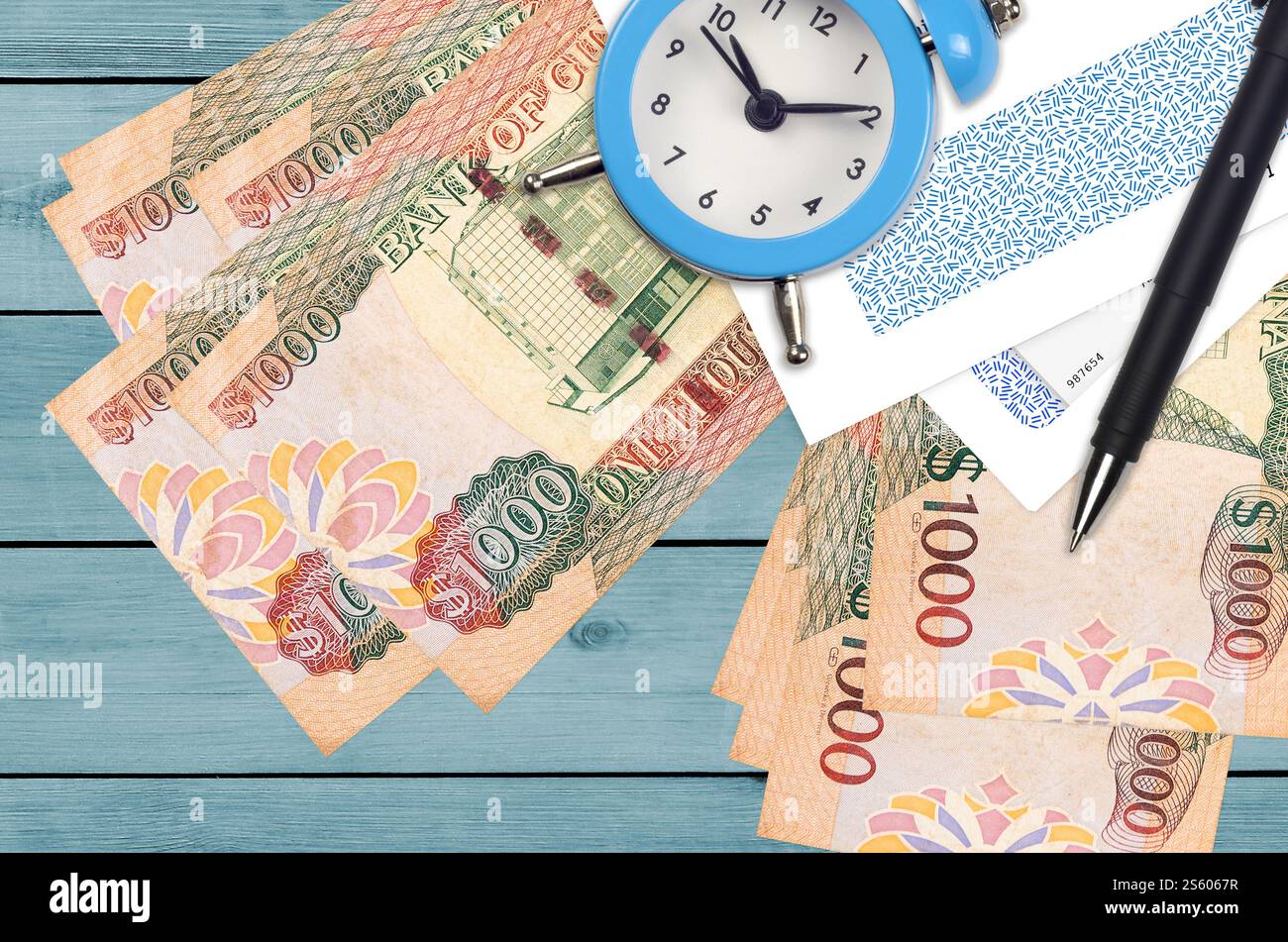 1000 Guyana-Dollar-Scheine und Wecker mit Stift und Umschlägen. Steuersaisonkonzept, Zahlungsfrist für Kredit oder Darlehen. Finanzoperationen Stockfoto