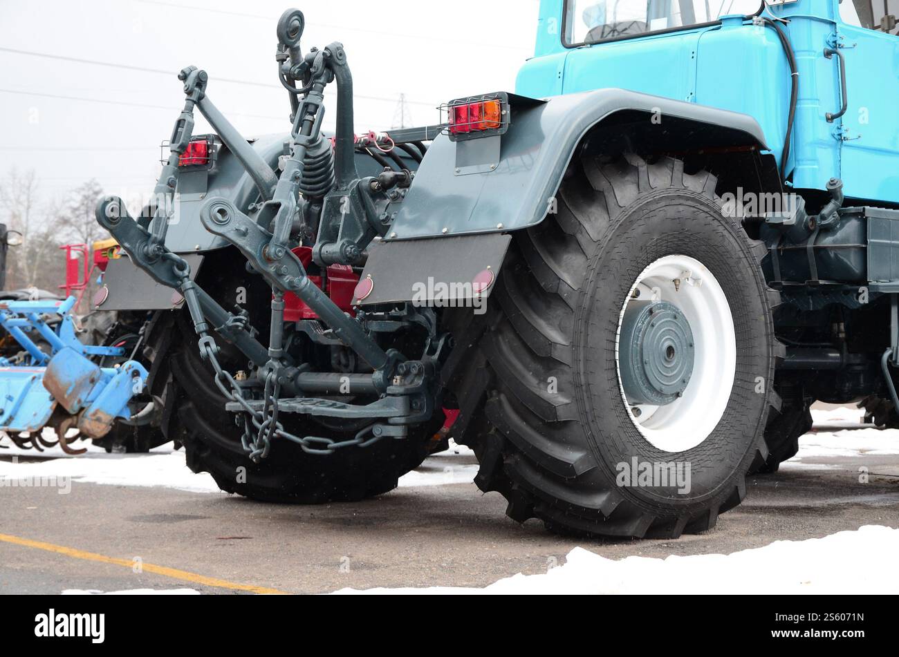 Räder der Rückansicht des neuen Traktors bei Schnee. Rückansicht des landwirtschaftlichen Fahrzeugs. Räder der Rückansicht des neuen Traktors bei Schnee. Stockfoto