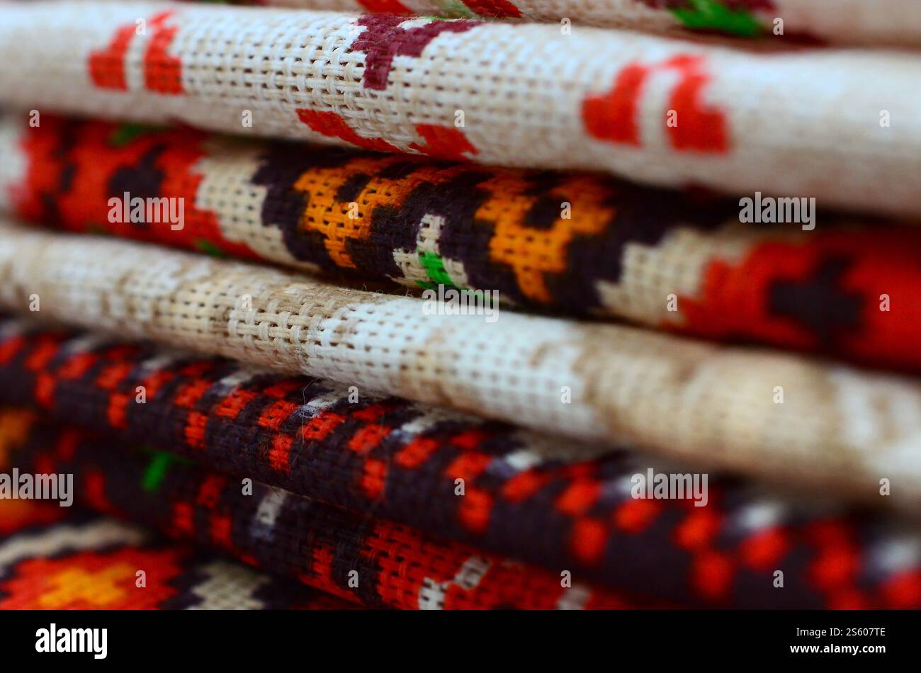 Stapel traditioneller ukrainischer Stickmuster auf Textilgewebe. Gestricktes Canvas mit farbigem Pixeldesign. Stapel traditioneller Produkte Stockfoto