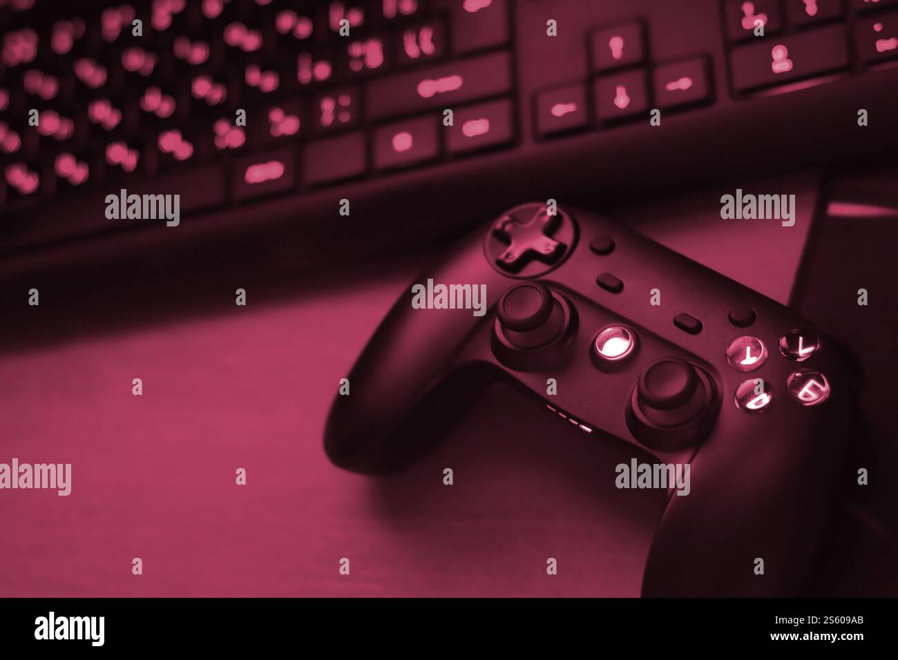 Modernes Gamepad mit pc-Tastatur auf dem Tisch in dunkler Spielzimmerszene aus nächster Nähe. Gameplay-Streaming und Videospiel-Rundgänge Konzept Bild eingespielt Stockfoto