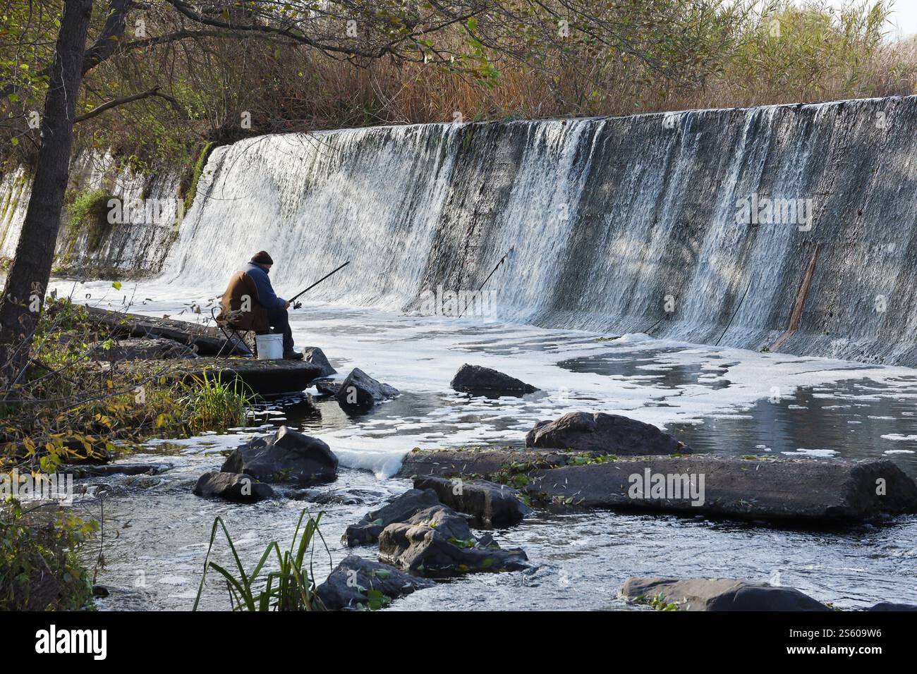 Ein stillgelegter Damm, ein künstlicher Wasserfall, der Damm der Butka HPP, befindet sich am Fluss hinter der Brücke über den Hirsky Tikich. Ein Stockfoto