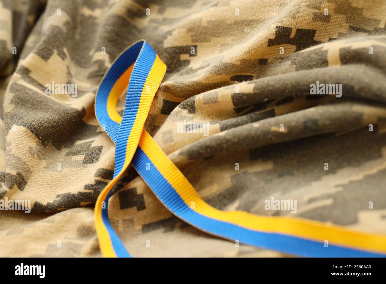Gepixelter, digitaler Militärtarnstoff mit Band in blauen und gelben Farben. Attribute der ukrainischen patriotischen Soldatenuniform. Gepixelt digital Stockfoto