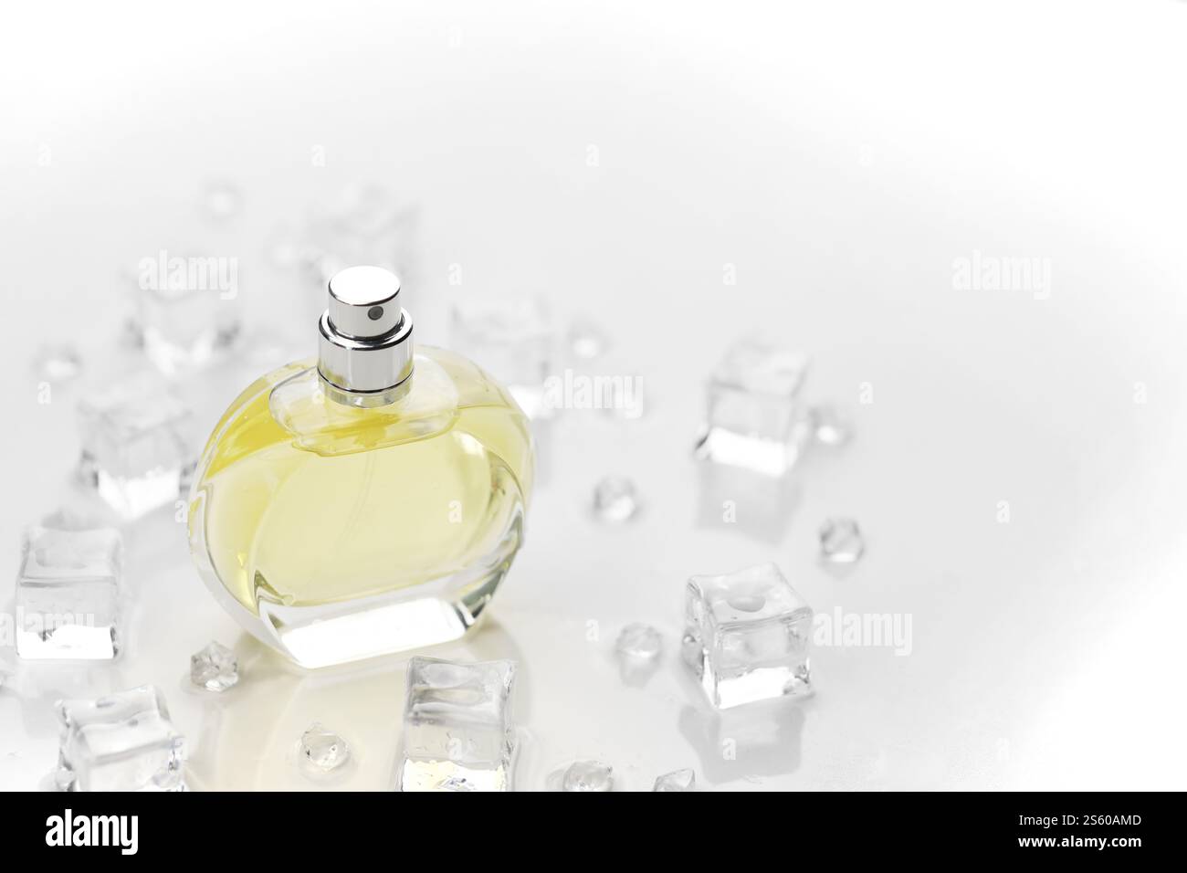 Weibliche Parfümflasche, objektive Fotografie der Parfümflasche in Eiswürfeln und Wasser auf weißem Tisch. Blick von oben. Modellbild Produktfoto, Stockfoto