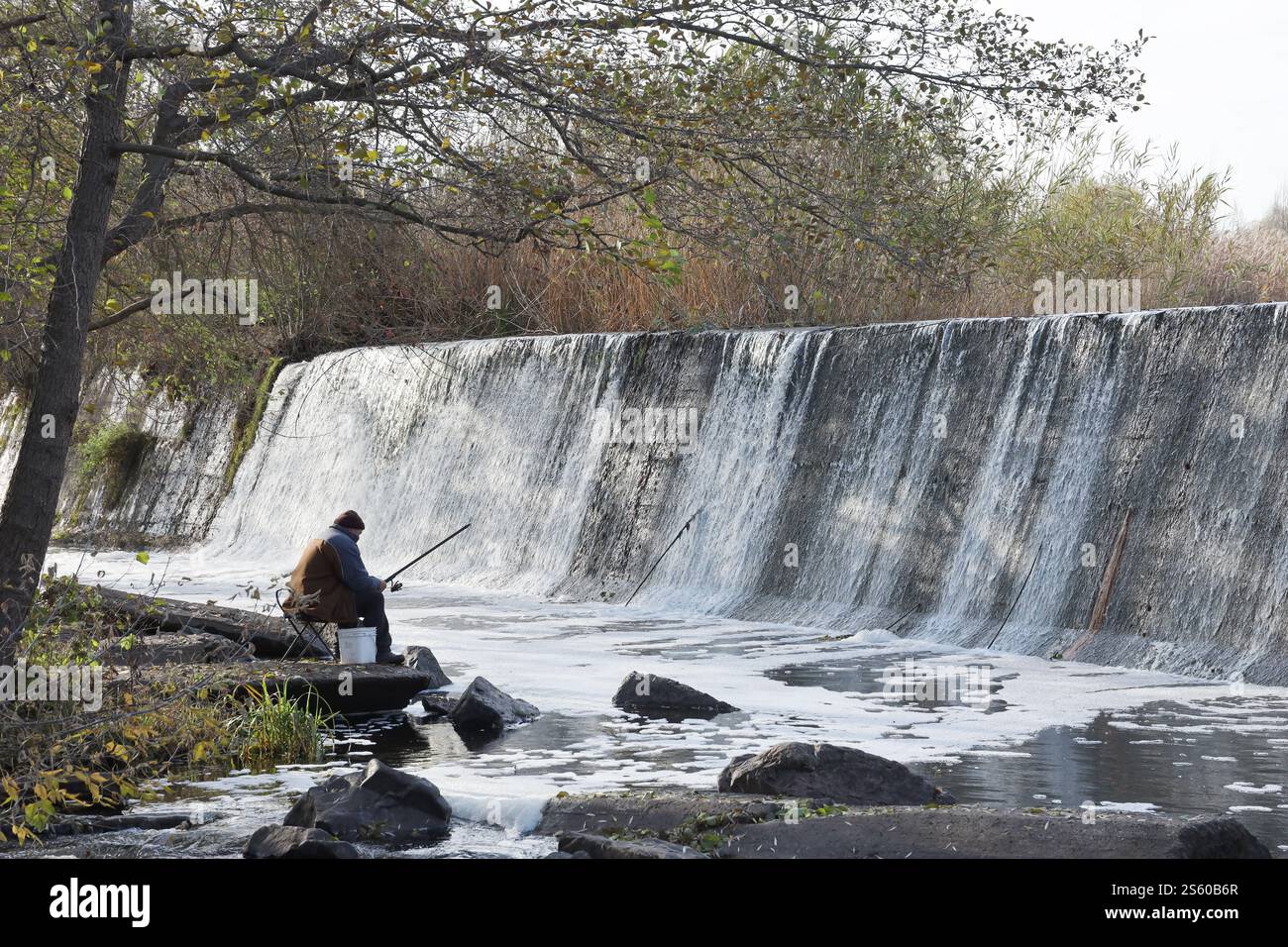Ein stillgelegter Damm, ein künstlicher Wasserfall, der Damm der Butka HPP, befindet sich am Fluss hinter der Brücke über den Hirsky Tikich. Ein Stockfoto