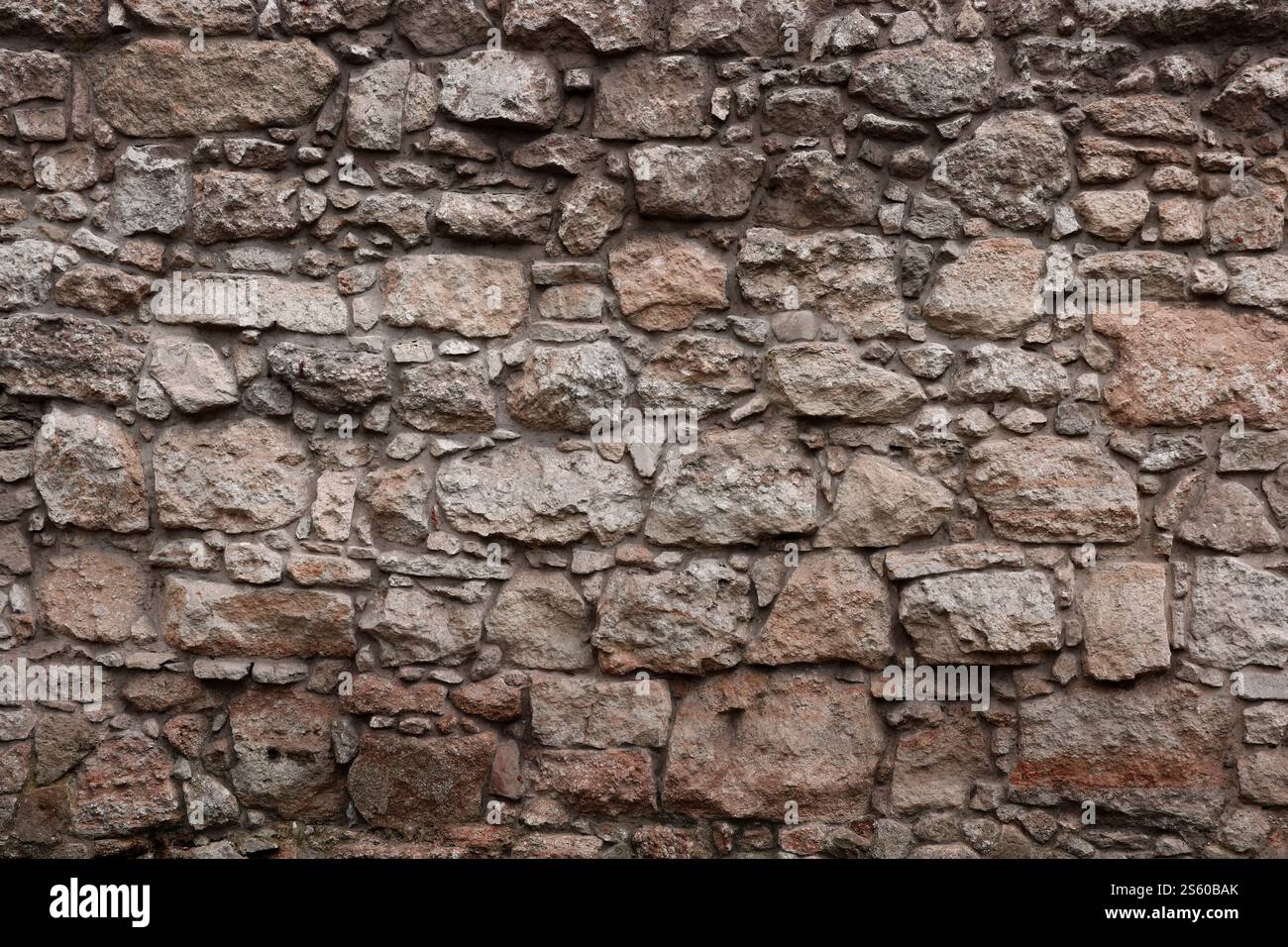 Textur einer Steinmauer mit vielen großen braunen und grauen Steinen, die mit Zement bewaffnet sind. Alte Burg Stein Wand Textur Hintergrund für mittelalterliche Nutzung. Teil eines Stockfoto