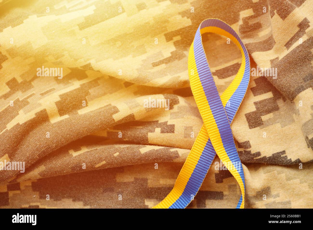 Gepixelter, digitaler Militärtarnstoff mit Band in blauen und gelben Farben. Attribute der ukrainischen patriotischen Soldatenuniform. Gepixelt digital Stockfoto