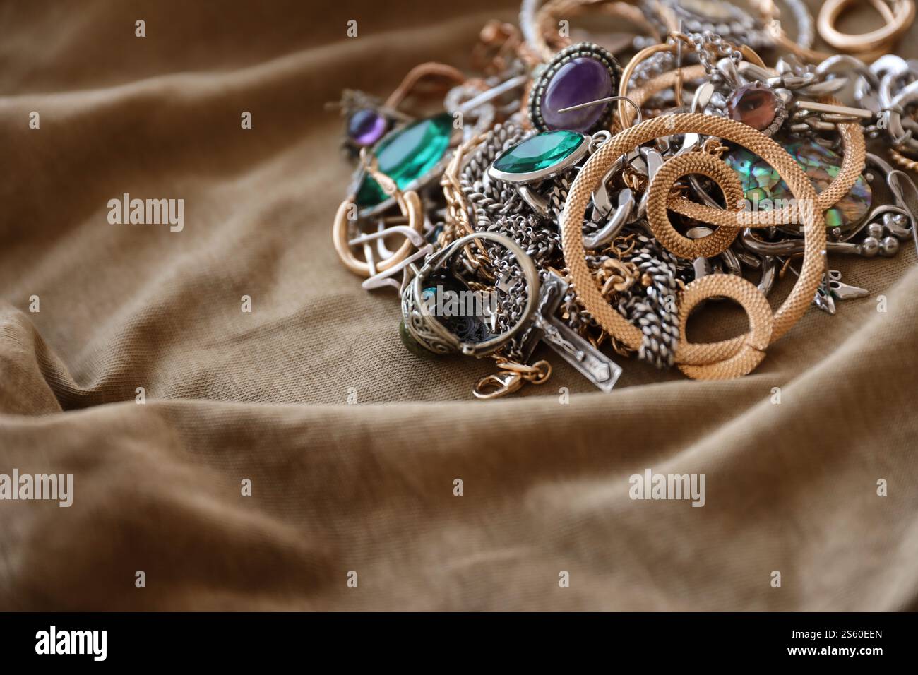 Ein Haufen gestohlener Schmuck auf Militäruniform-Stoff. Plünderung durch russische Soldaten in den ukrainischen Städten während des russischen Angriffs auf die Ukraine. Stockfoto