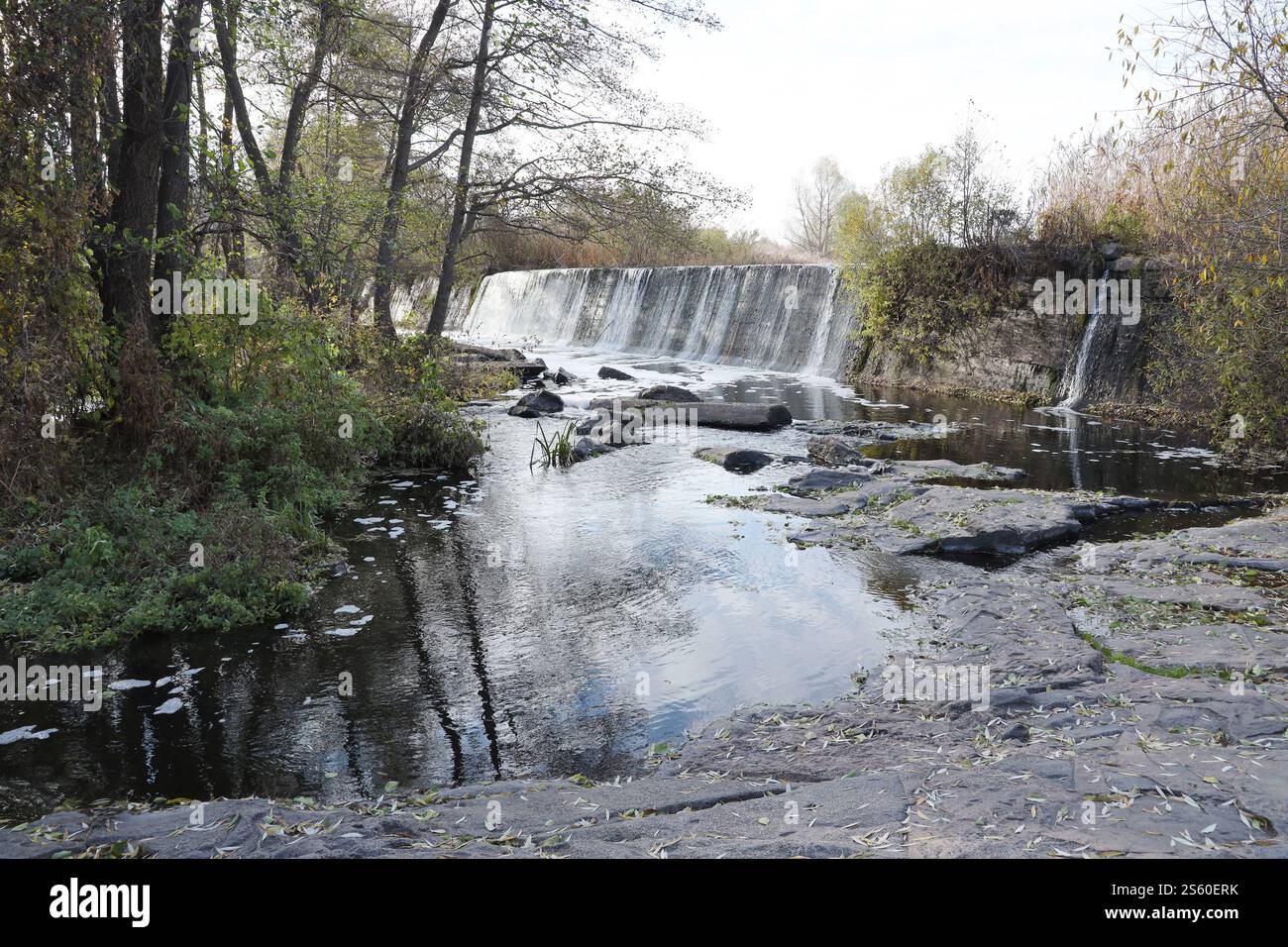 Ein stillgelegter Damm, ein künstlicher Wasserfall, der Damm der Butka HPP, befindet sich am Fluss hinter der Brücke über den Hirsky Tikich. Ein Stockfoto