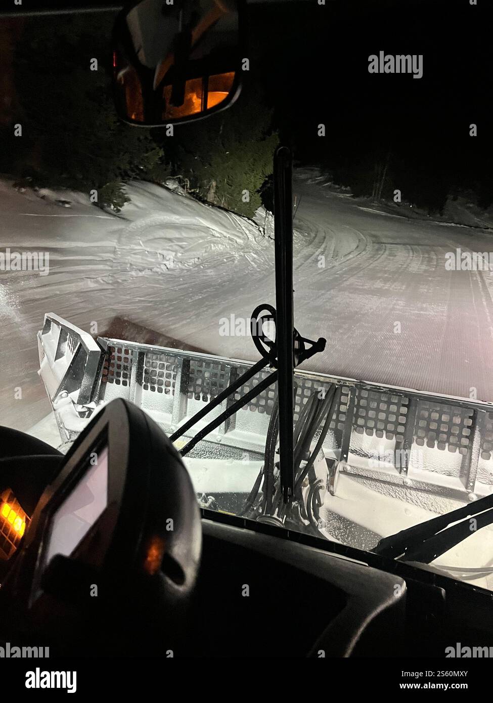 Schneepflug-Fahrer arbeiten fleißig daran, nachts eine schneebedeckte Bergstraße zu räumen und sich durch die Herausforderungen des Winterwetters zu bewegen Stockfoto
