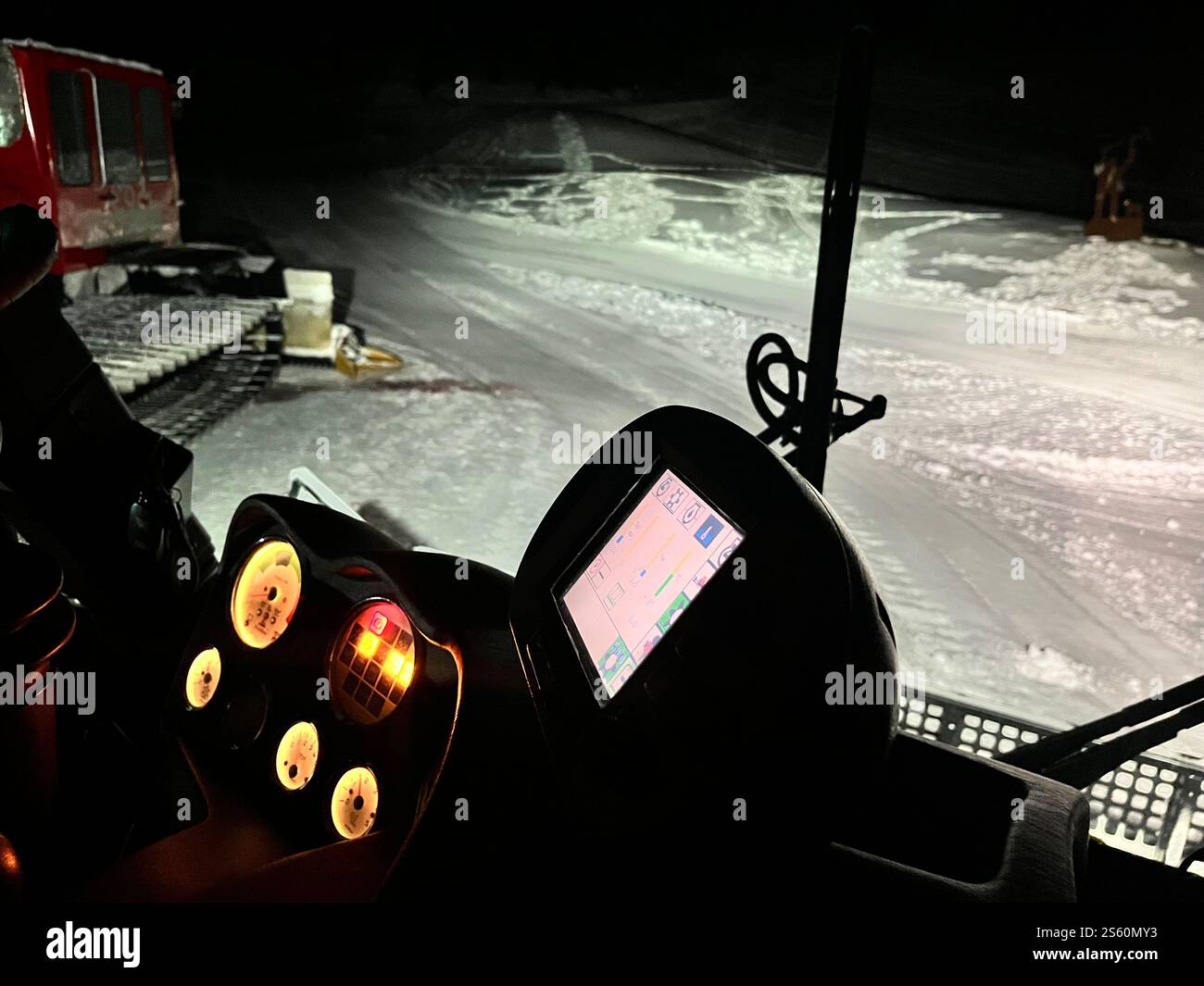 Beleuchtetes Armaturenbrett einer Schneekatze, mit GPS und Bedienelementen, die nachts für die Pflege einer Skipiste in einem Winterresort arbeiten Stockfoto