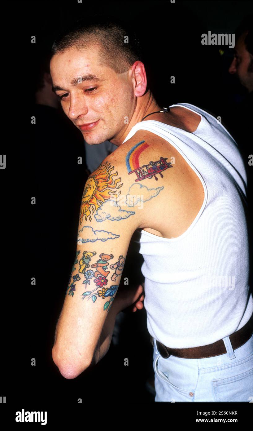 Der junge Mann zeigt bunte Tattoos, während er einen Abend im Paradiso im lebhaften Nachtleben Amsterdams genießt Stockfoto