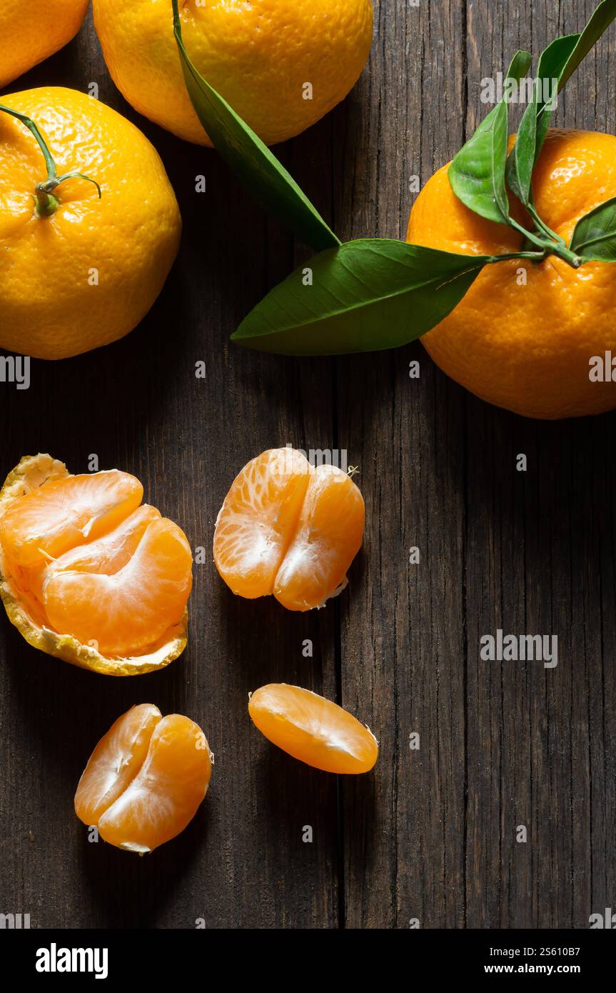 Frische reife saftige gelbe Mandarine ( Clementine, Mandarine ) auf rustikalem Vintage-Tisch mit Blatt. Winterfrucht Hintergrundkonzept Stockfoto