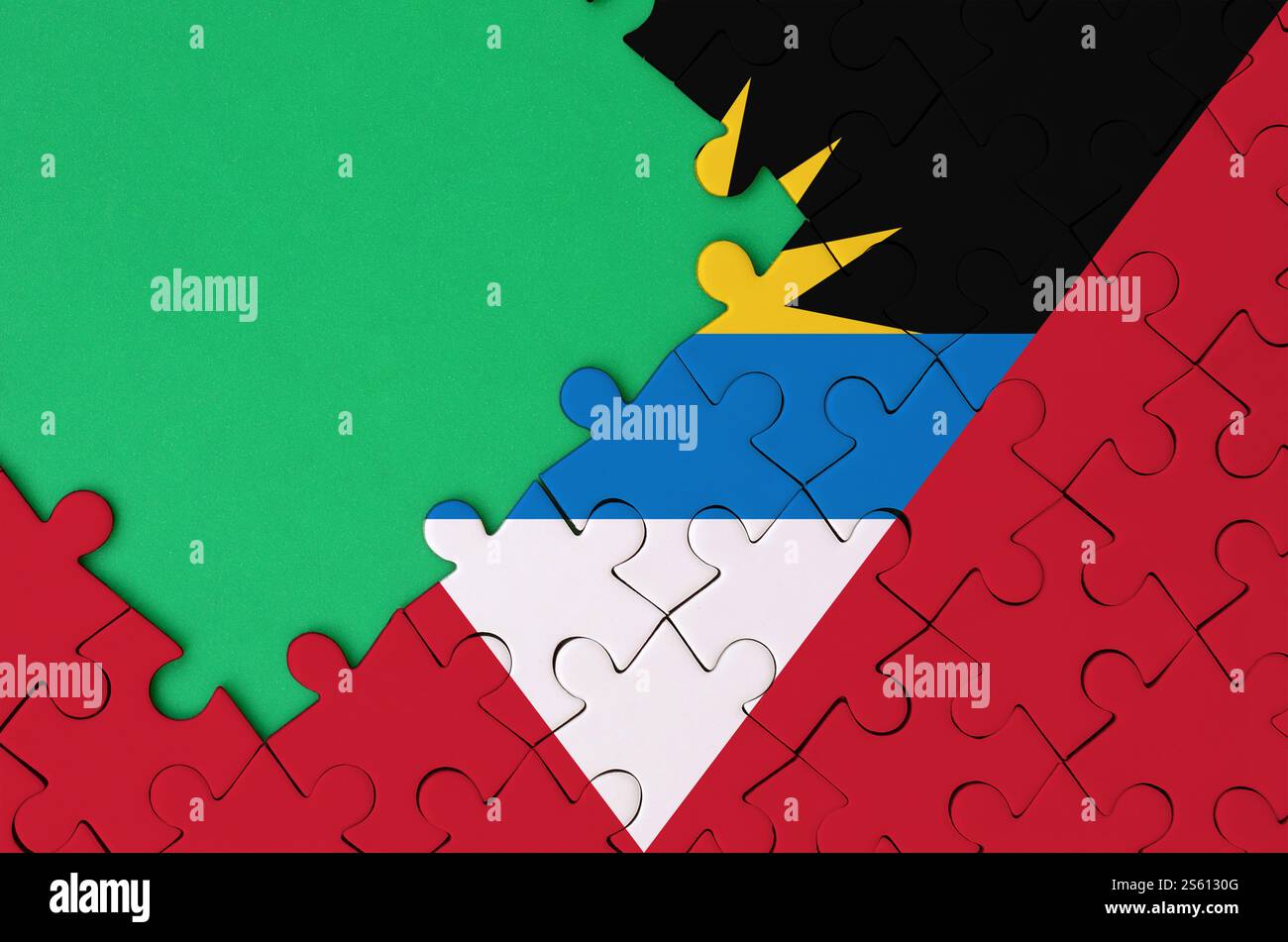 Antigua und Barbuda Flagge ist auf einem fertigen Puzzle mit freiem grünen Kopierraum auf der linken Seite dargestellt. Die Flagge von Antigua und Barbuda ist abgebildet Stockfoto