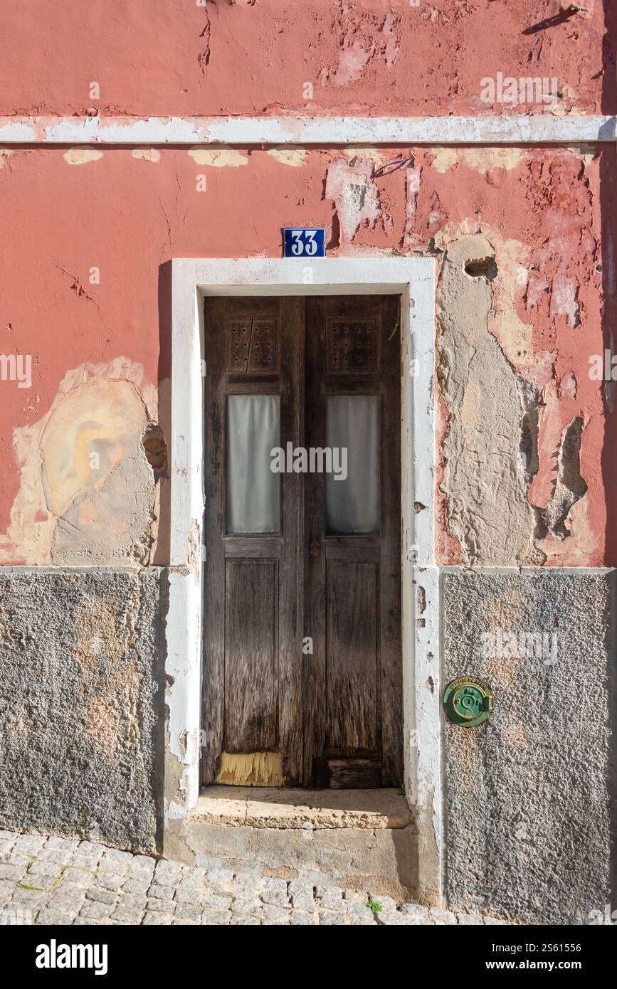 Alte Holztür in einer verwitterten und rissigen Putzwand Stockfoto