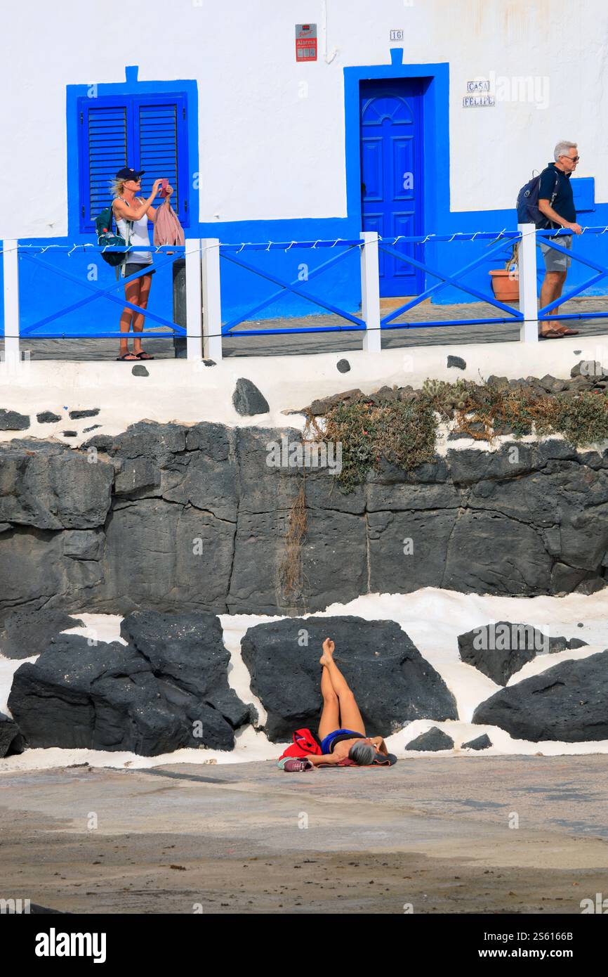 Frau, die auf dem Rücken liegend und die Beine gegen Felsen angehoben ist, Sonnenbaden, El Cotillo, Fuerteventura, Kanarische Inseln, Spanien. Stockfoto