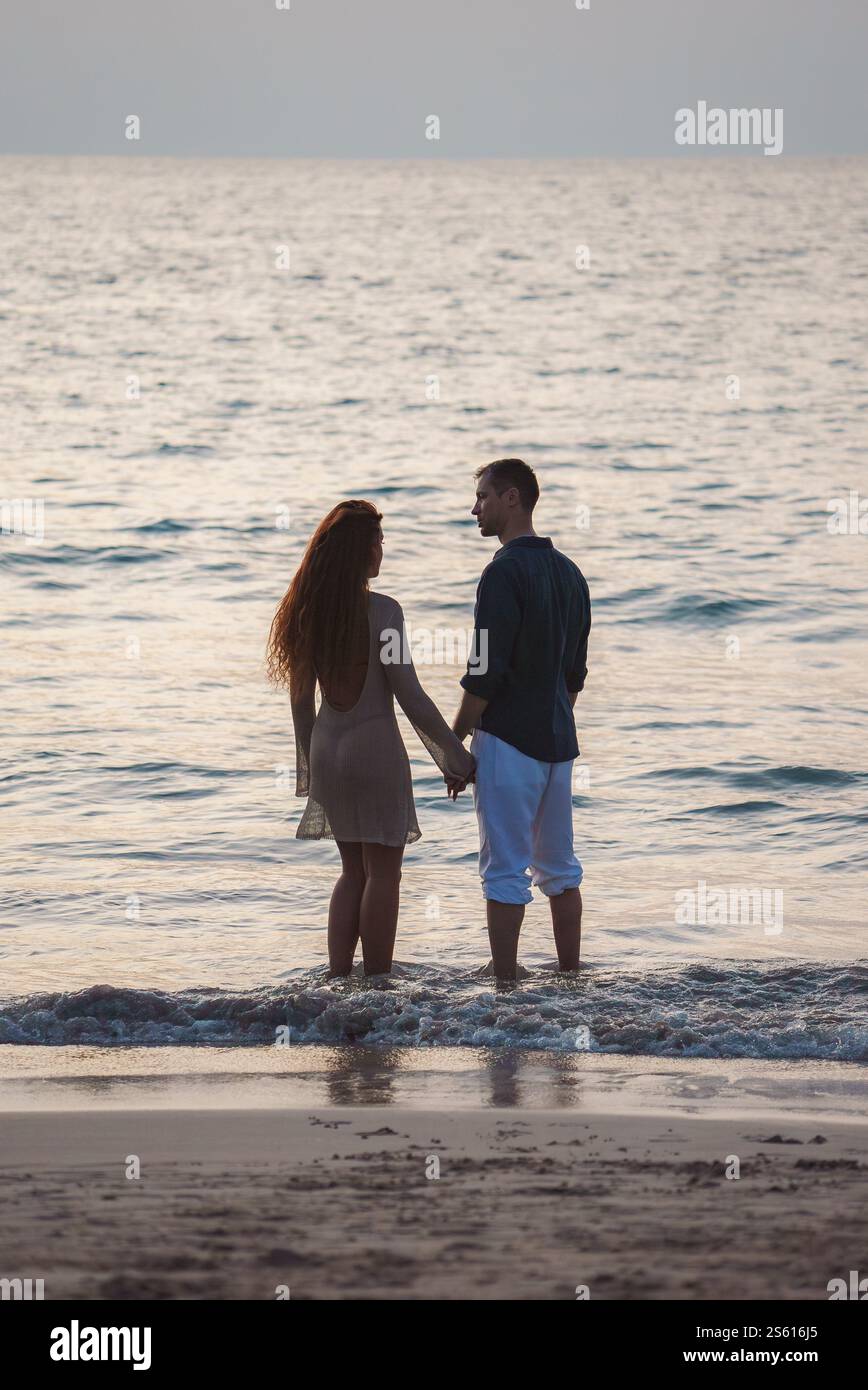 Ein Paar, das Hände an einem Sandstrand in Thailand hält Stockfoto