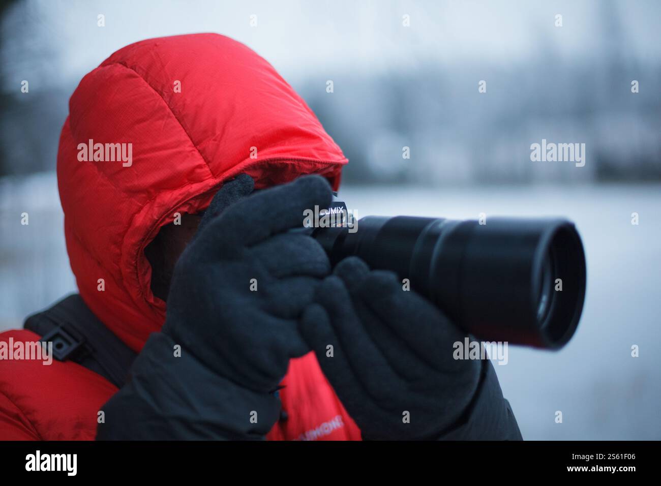 Ein Fotograf in einem knallroten Mantel, der im Winter fotografiert Stockfoto