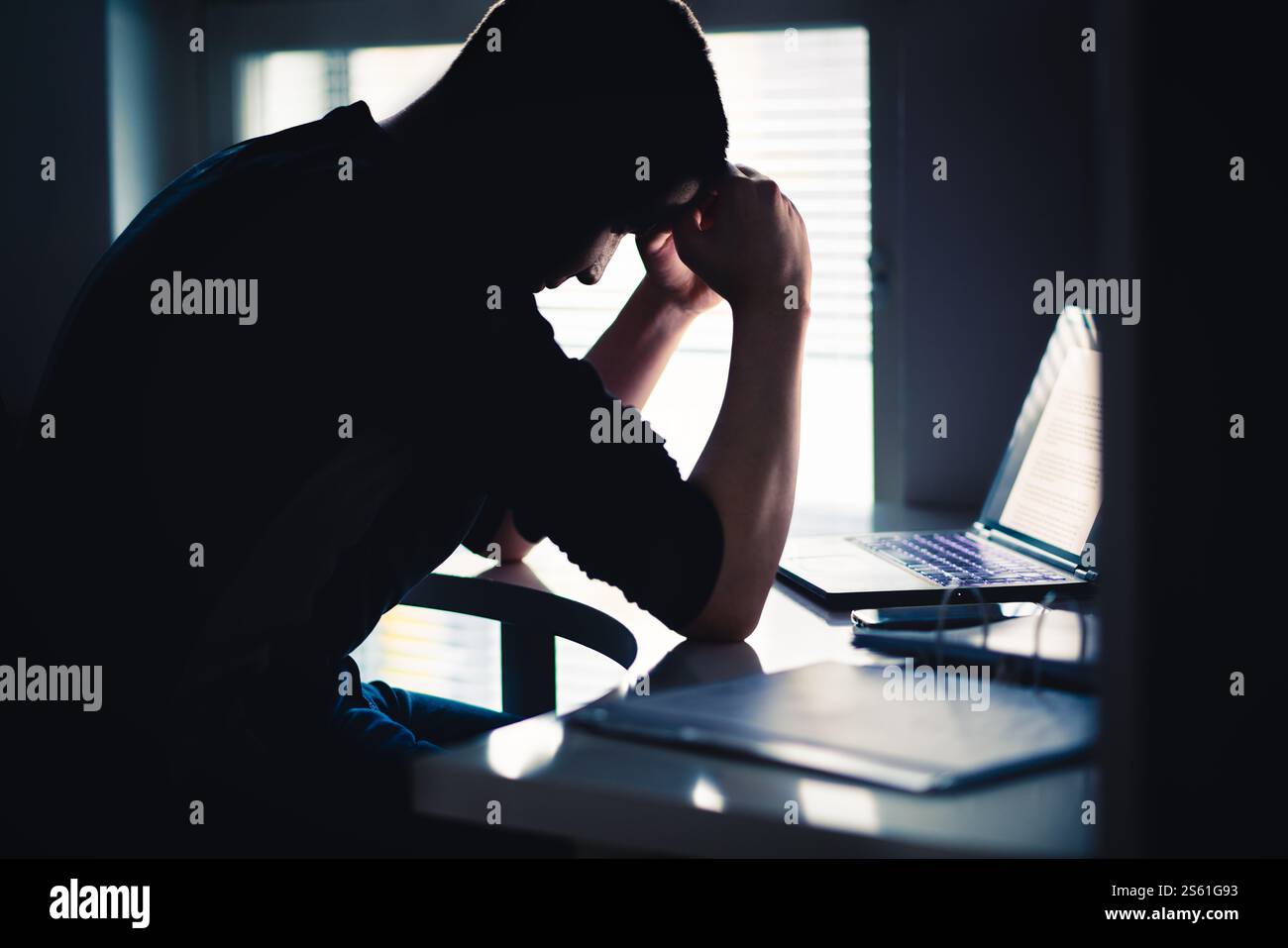 Stress am Arbeitsplatz. Müder Mann mit Angst. Trauriger Büroangestellter mit Laptop. Frustrierter Student oder Student. Dunkle Silhouette eines ängstlichen Menschen. Stockfoto