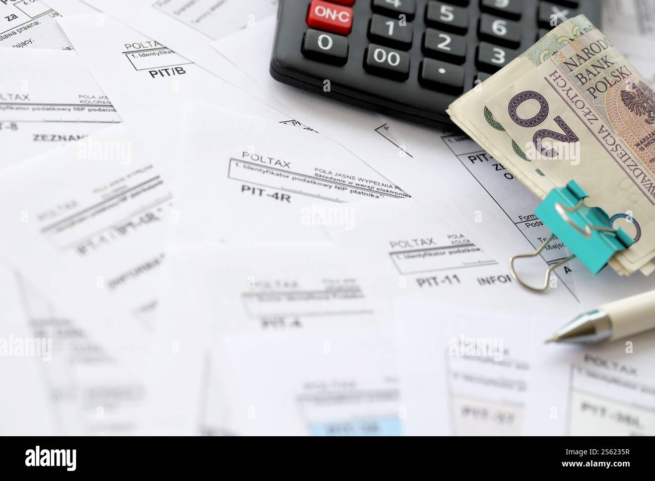 Polnisches Zloty-Geld PLN, Taschenrechner und Stift auf einer großen Menge polnischer PIT-, CIT- und Mehrwertsteuerformulare aus nächster Nähe. Buchhaltung, Bürokratie und Steuerzahler Stockfoto