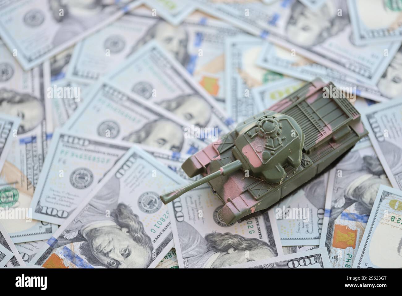 Spielzeugtank auf US-Dollar-Banknoten aus nächster Nähe. Das Konzept der Kriegskosten, der Militärausgaben und der Wirtschaftskrise. Spielzeugtank auf US Hundred Stockfoto