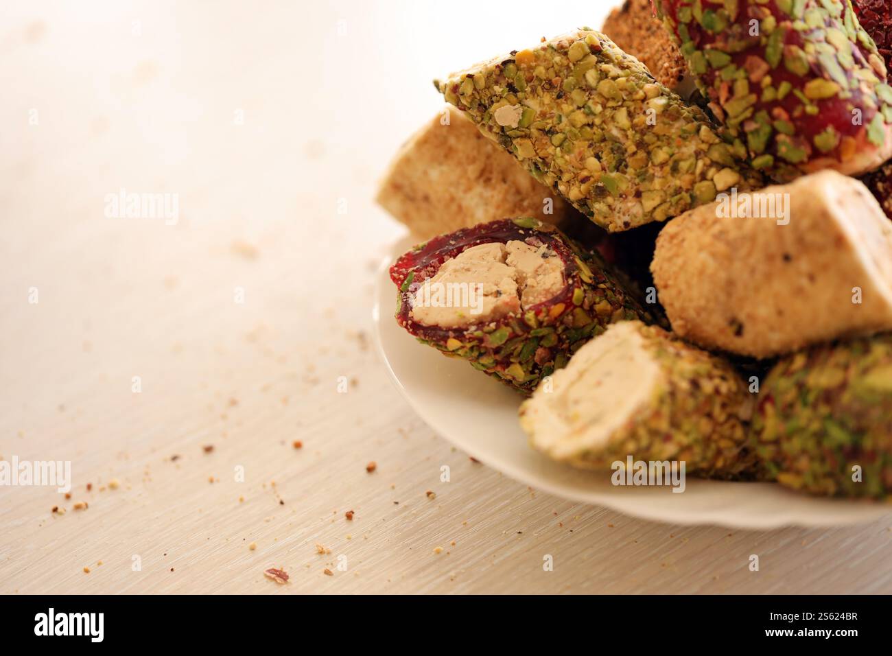 Viele Rollen türkischer Delikatesse mit verschiedenen Aromen und Füllungen auf weißem Teller auf dem Tisch. Teile von türkischen Lokumu-Süßigkeiten. Viele Rollen türkischer Delikatessen Stockfoto