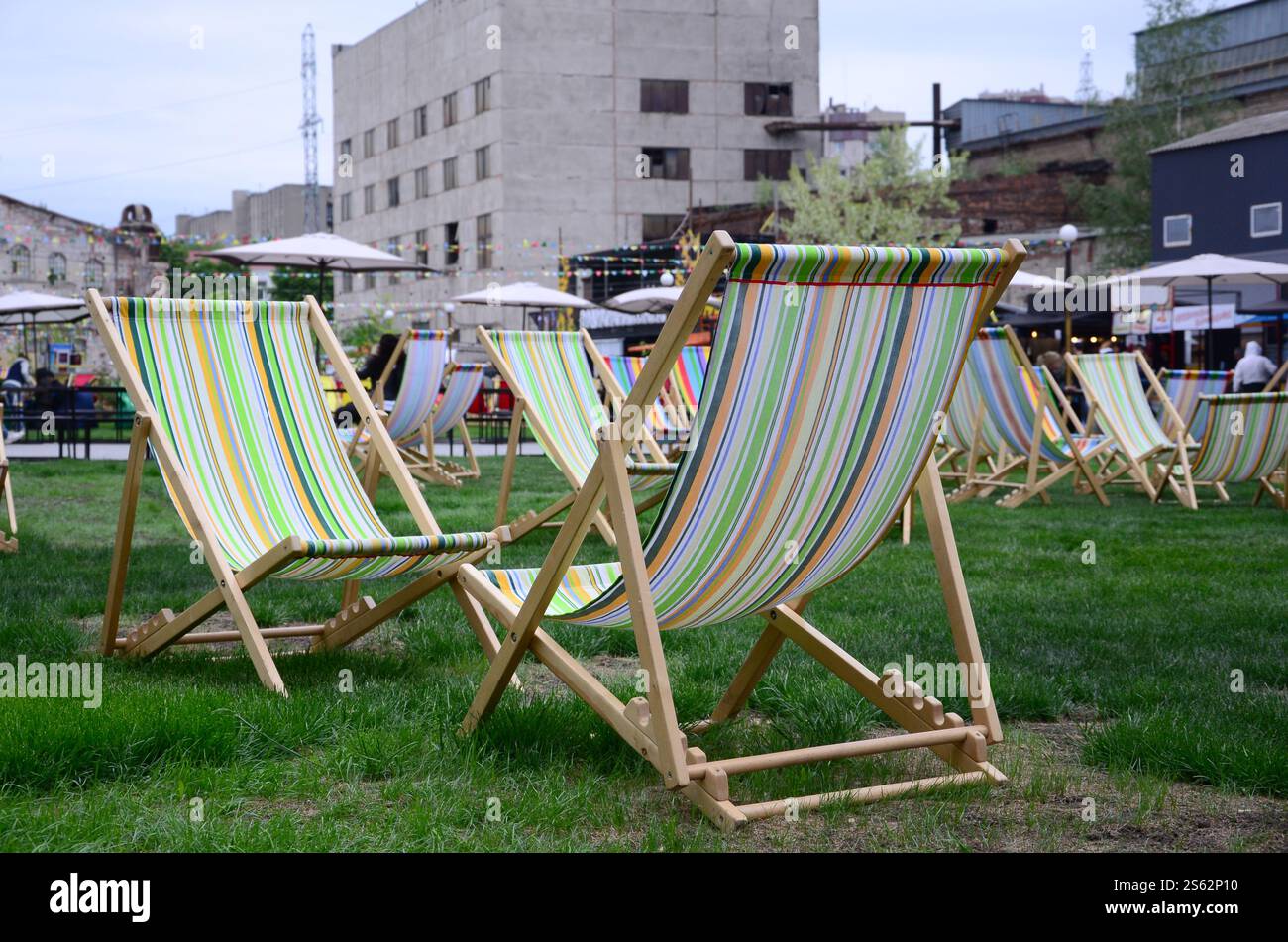 Liegestühle auf einem Rasen. Ruhen Sie sich auf dem Festival aus, im Urlaub. Gartenliegen auf grünem Gras. Gartenbett zum Sonnenbaden und Ausruhen. Sommerstuhl. Chaise Stockfoto