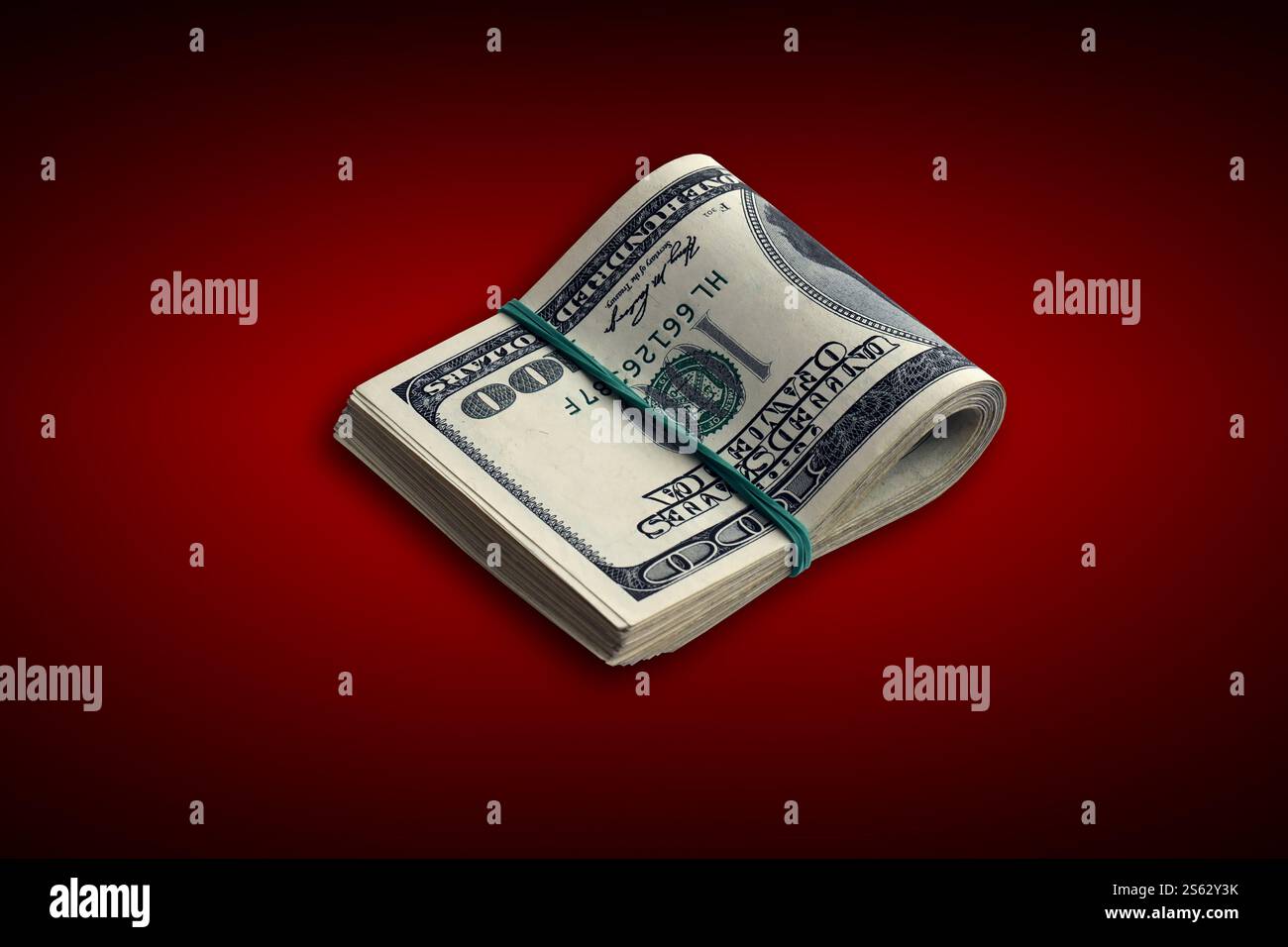 Ein Bündel von US-Dollar-Scheinen auf purpurrotem Hintergrund. Packung amerikanisches Geld mit hoher Auflösung auf dunkelrotem Hintergrund mit dunkler Vignette. Bündel von Stockfoto