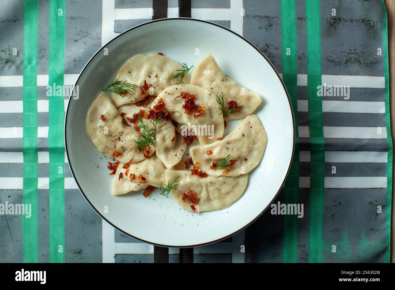 Varenyky oder Teigtaschen mit gebratenen Zwiebeln und Dill, serviert auf weißem Teller Stockfoto