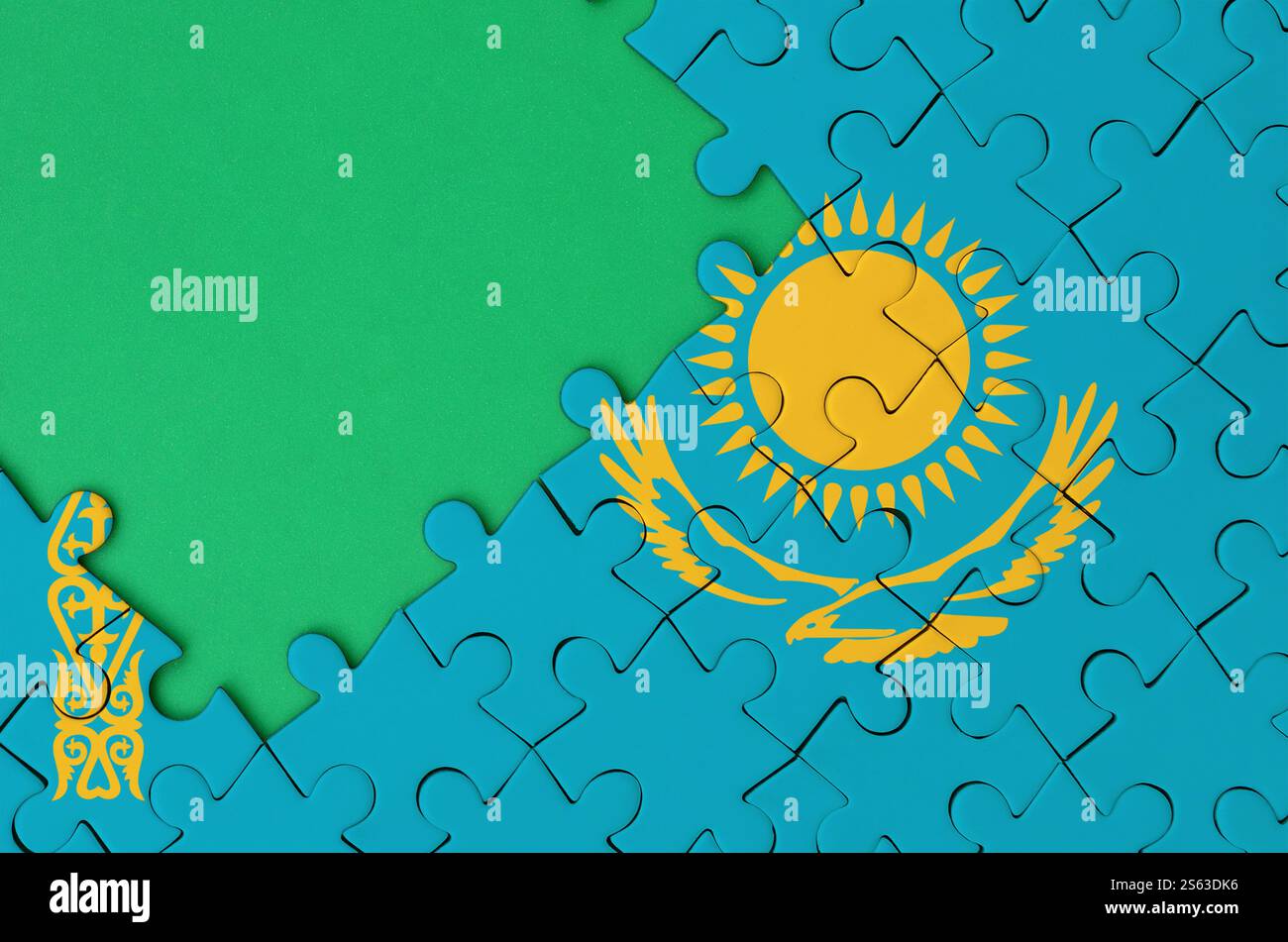 Kasachstans Flagge ist auf einem fertigen Puzzle mit freiem grünen Kopierraum auf der linken Seite abgebildet. Kasachstans Flagge ist auf einem fertig gestellten abgebildet Stockfoto