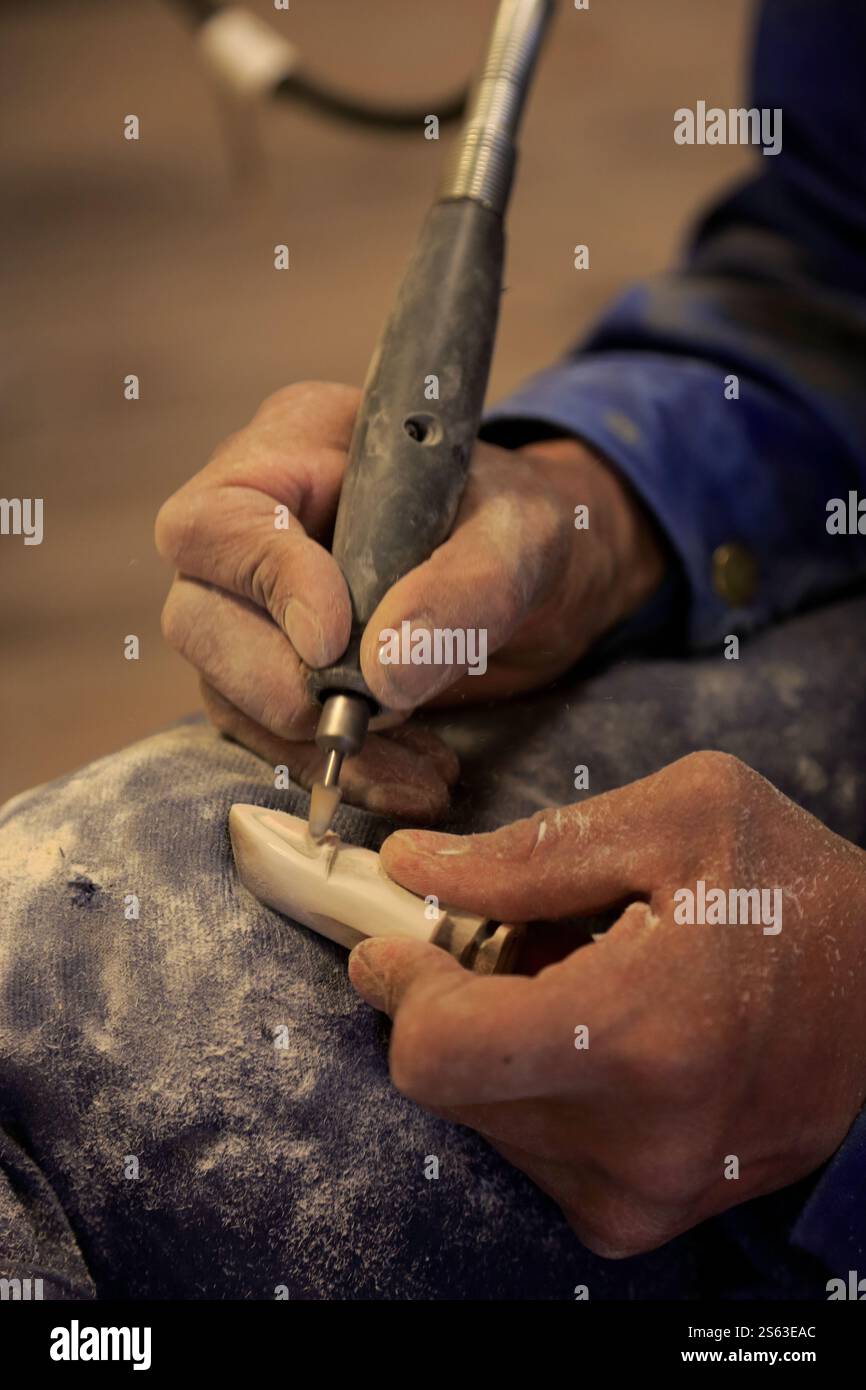 Ein geschlossener Blick auf die Hände eines Inuit-Handwerkers, um ein traditionelles Walknochen-Schnitzerei herzustellen. Sisimiut. Gemeinde Qeqqata. Grönland Stockfoto