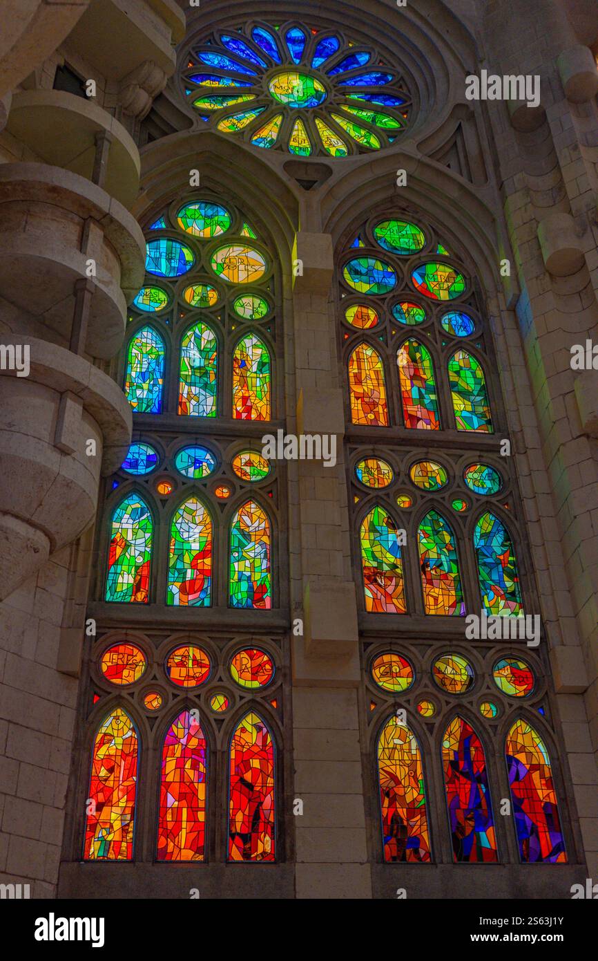 Regenbogenfarbene Buntglasfenster in der Sagrada Familia, Barcelona, geben lebendiges Licht und verleihen Gaudí ikonischer Kunst einen faszinierenden Touch. Stockfoto