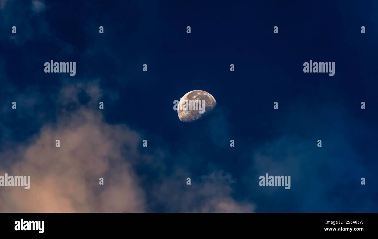 Abnehmender Mond, der durch die Morgenwolken pierct Stockfoto