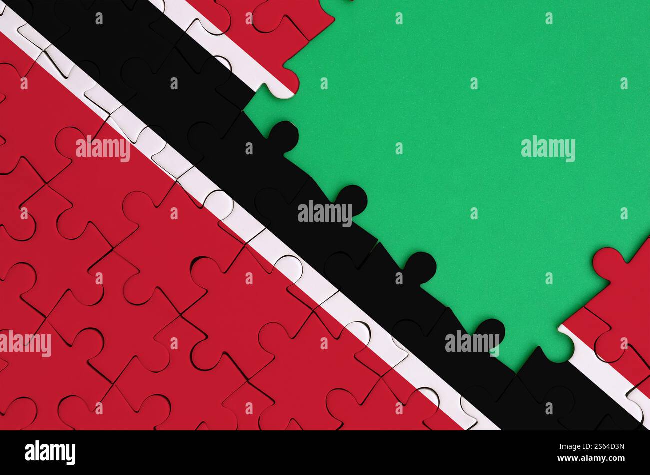 Die Flagge von Trinidad und Tobago ist auf einem fertigen Puzzle mit einem freien grünen Kopierraum auf der rechten Seite abgebildet. Die Flagge von Trinidad und Tobago ist abgebildet Stockfoto