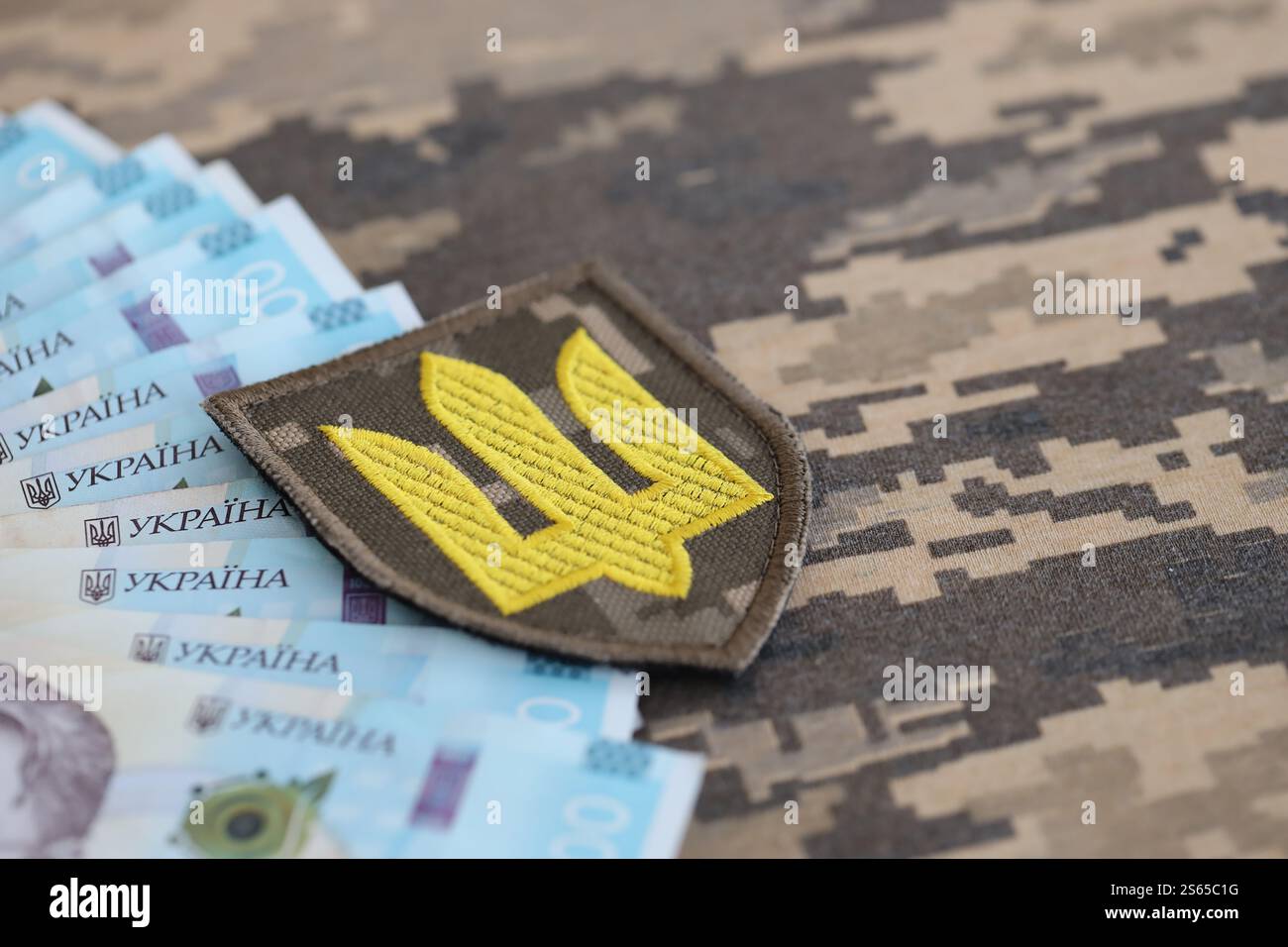 Ukrainisches Armeesymbol und Hrywna-Rechnungen auf Militäruniform. Zahlungen an Soldaten der ukrainischen Armee, Gehälter an das Militär. Krieg in Stockfoto Ukrainisches Armeesymbol und Hrywna-Rechnungen auf Militäruniform. Zahlungen an Soldaten der ukrainischen Armee, Gehälter an das Militär. Krieg in Stockfoto