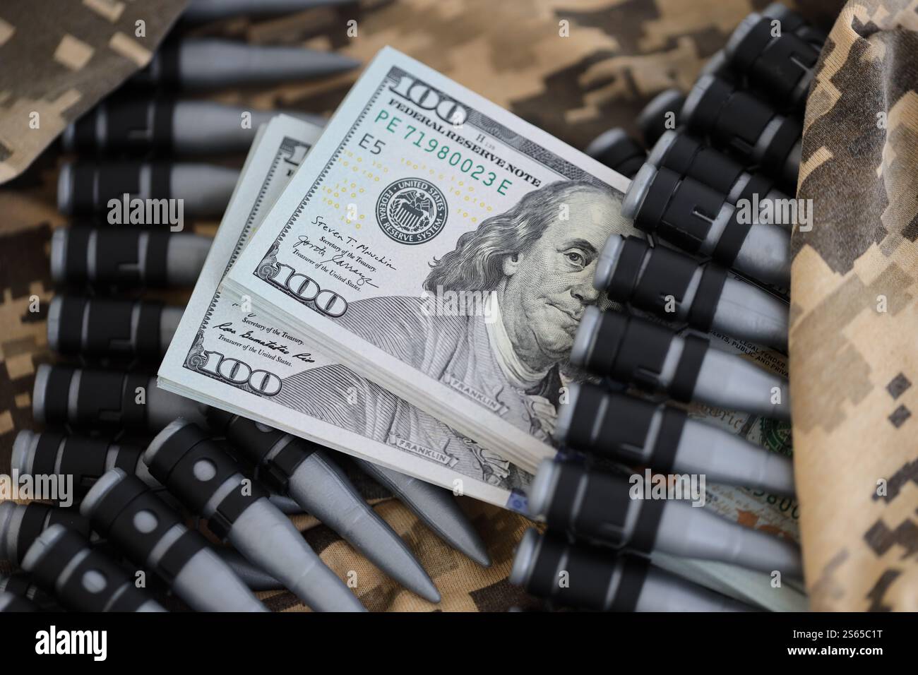 Dollarbündel und ein Maschinengewehrgürtel auf der Tarnuniform eines ukrainischen Soldaten. Konzept der Kriegsfinanzierung, Bestechung oder Spende. Hilfe zu Stockfoto