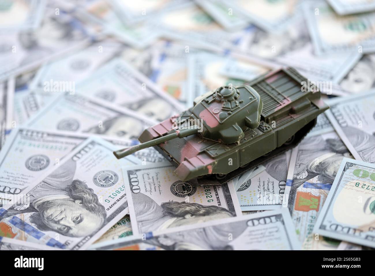 Spielzeugtank auf US-Dollar-Banknoten aus nächster Nähe. Das Konzept der Kriegskosten, der Militärausgaben und der Wirtschaftskrise. Spielzeugtank auf US Hundred Stockfoto