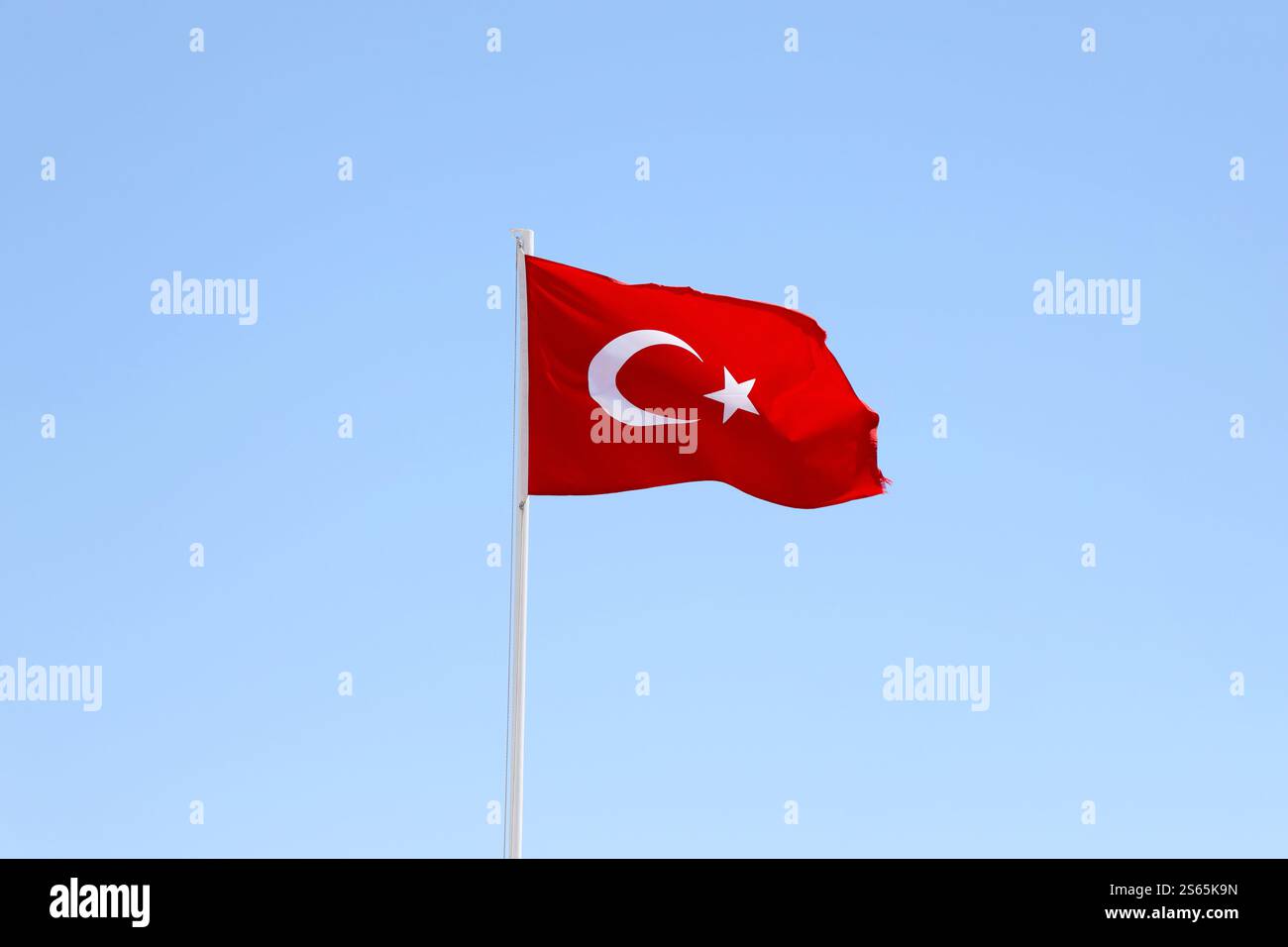 Türkische Flagge auf Fahnenmast winkt im Hintergrund des sauberen blauen Himmels. Weißer Halbmond und Stern auf rotem Hintergrund. Türkische Flagge auf Fahnenmast winkt sauber Stockfoto