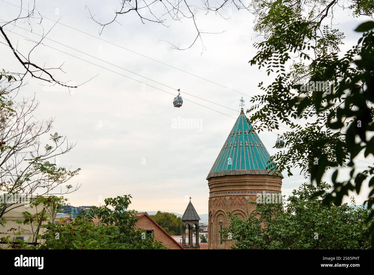 Reisen Sie nach Georgien - Seilbahnpark Rike - Narikala Kutsche über der grünen Kuppel der armenischen St. George Kirche in der alten Stadt Tiflis am Herbstabend Stockfoto