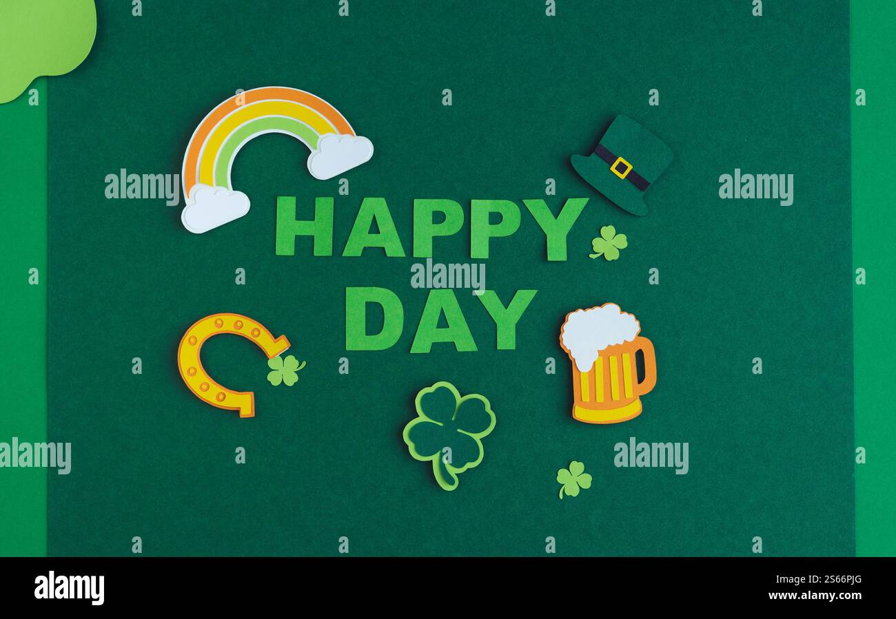 Ein grüner Hintergrund mit einem Regenbogen, Klee und einem Kleeblatt. In der Mitte stehen die Worte „Happy Day“ Stockfoto
