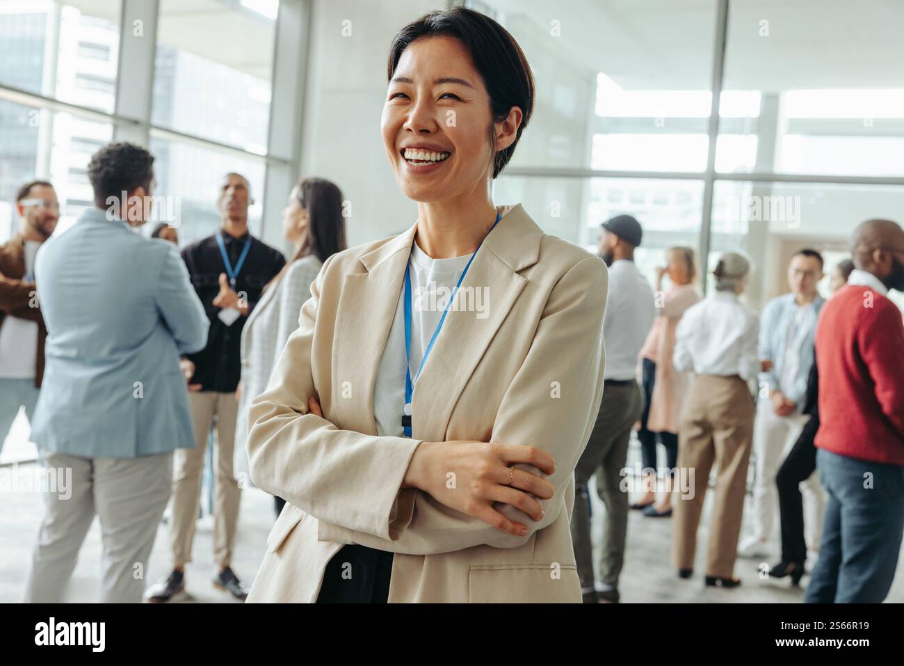 Lächelnde koreanische Geschäftsfrau, die gerne auf einer Konferenz Networking macht. Verschiedene Fachleute, die in einem modernen Konferenzumfeld Gespräche führen. Stockfoto
