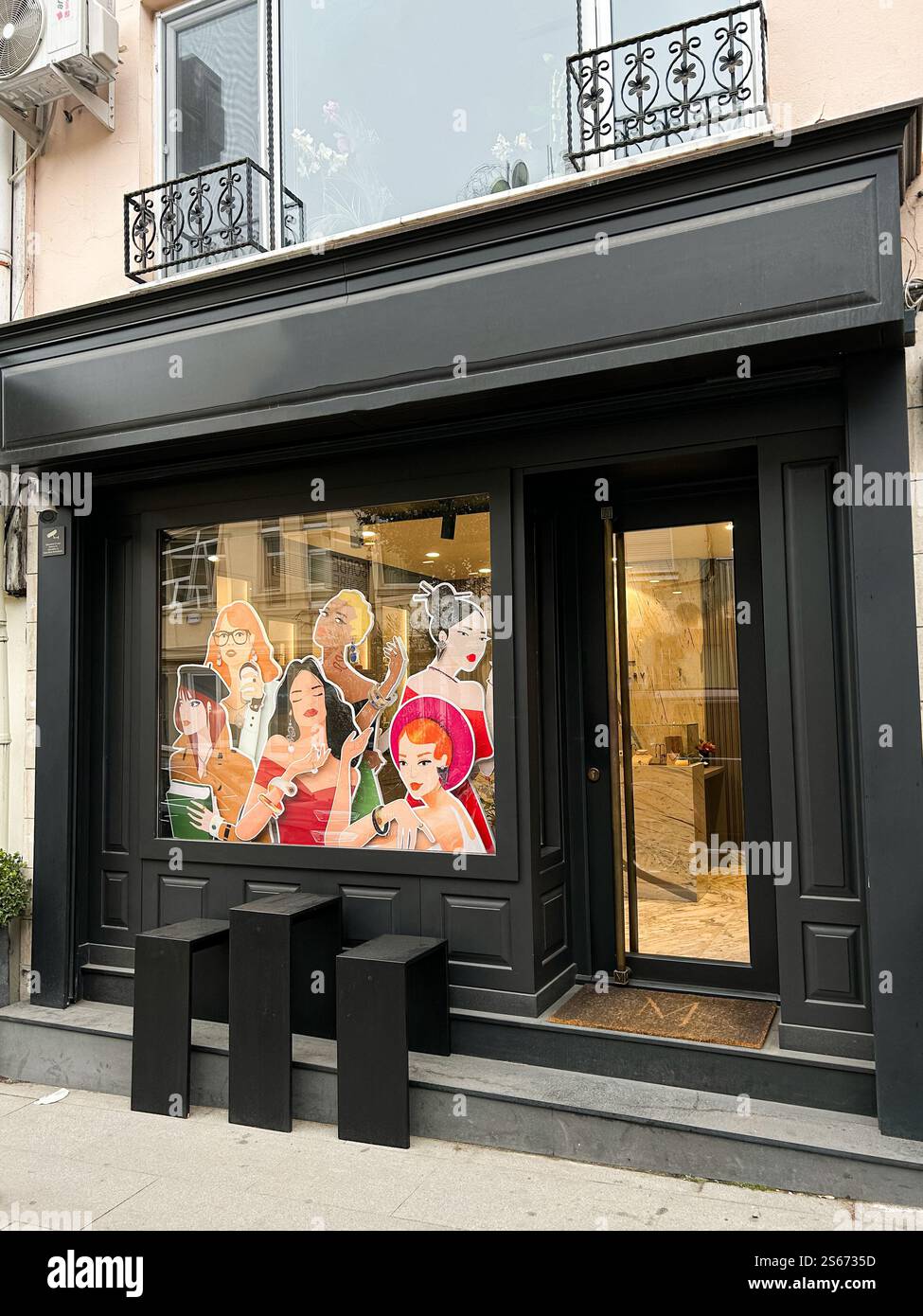 Dieses Foto zeigt ein stilvolles schwarz lackiertes Ladenlokal in Istanbul während der Frühlingssaison. Die lebendige Schaufensteranzeige zeigt künstlerische Illustrationen Stockfoto