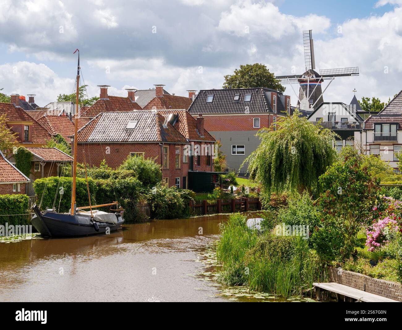 Blick auf den Hafen Winsumerdiep und die Windmühle von Jeneverbrug in der historischen Stadt Winsum, Groningen, Niederlande Stockfoto