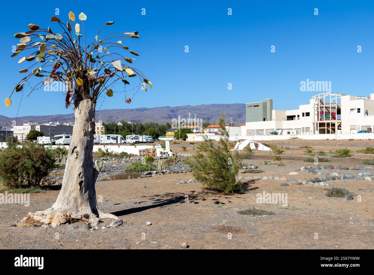 Kreatives Schulkunstprojekt mit einem Baum, der mit bunten handgefertigten Ornamenten vor einem klaren blauen Himmel verziert ist. Stockfoto