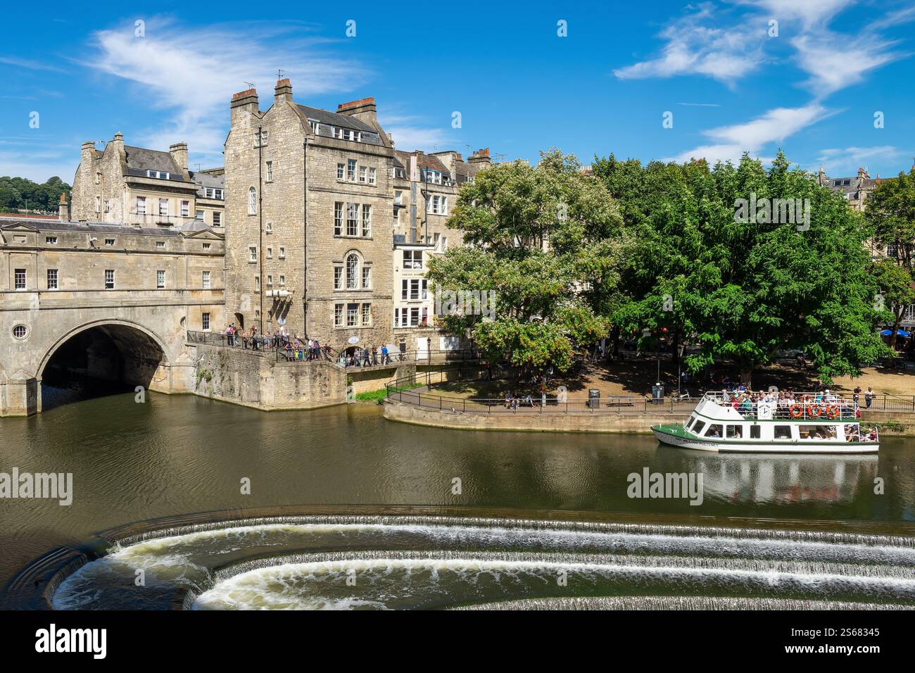 Touristenboot, das nahe der berühmten Pulteney Brücke und dem Pulteney Weir auf dem Fluss Avon in Bath, England, vor Anker liegt. Stockfoto