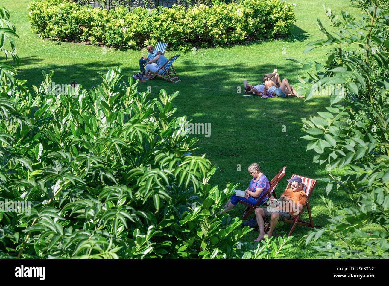 Leute, die sich entspannen und Bücher lesen in Parade Gardens, Bath, Großbritannien. Sie genießen die friedliche Atmosphäre und die malerische Aussicht im öffentlichen Park. Stockfoto